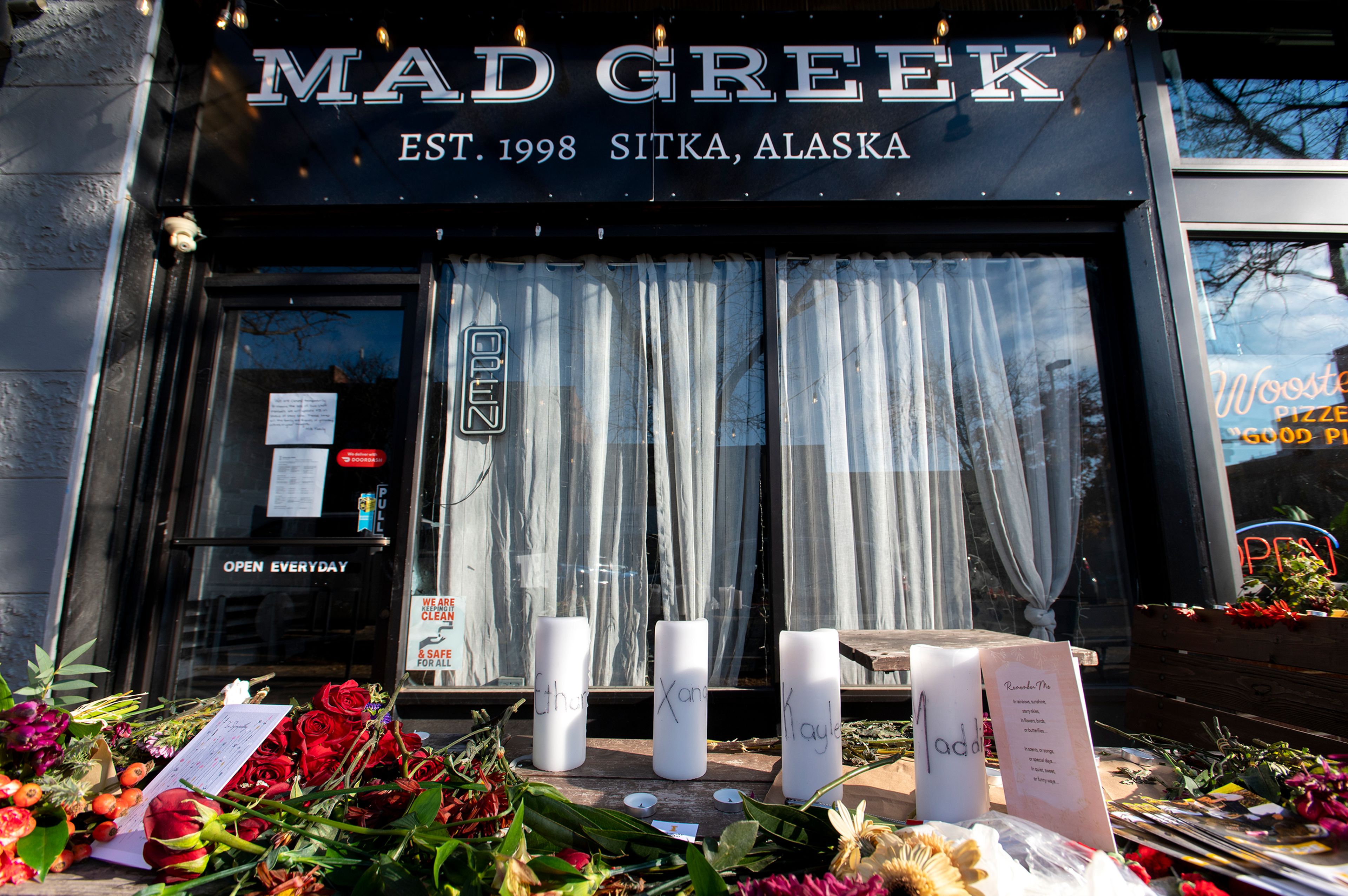 Candles and flowers rest on a table in honor of four deceased University of Idaho students, including Madison Mogen and Xana Kernodle, who worked at Mad Greek in downtown Moscow, at a memorial put together by coworkers outside of the restaurant on Tuesday.