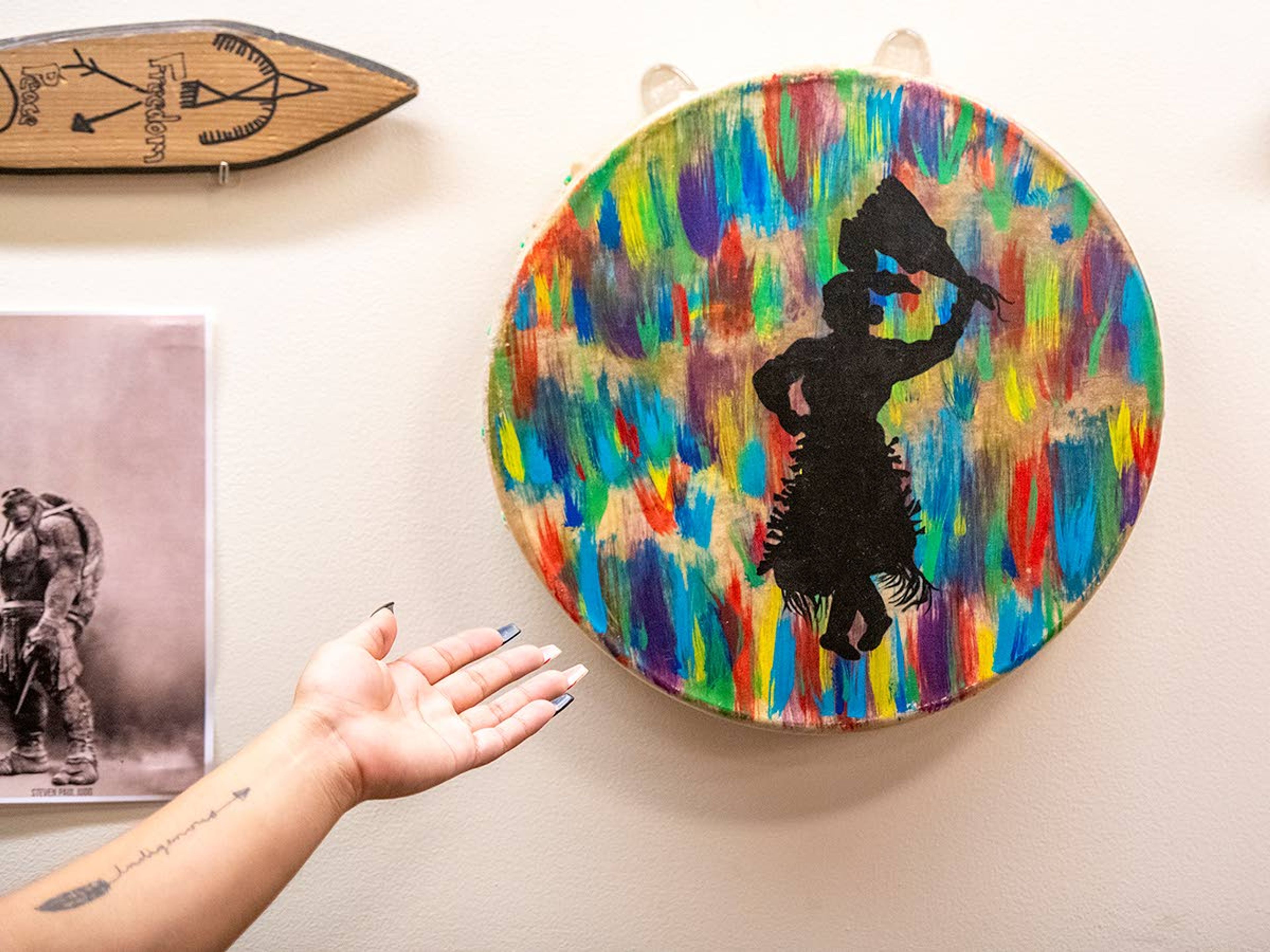 Mondejar points to a hand drum created by a cousin as a gift when Mondejar left for college. The center of the drum features the silhouette of a jingle dancer.