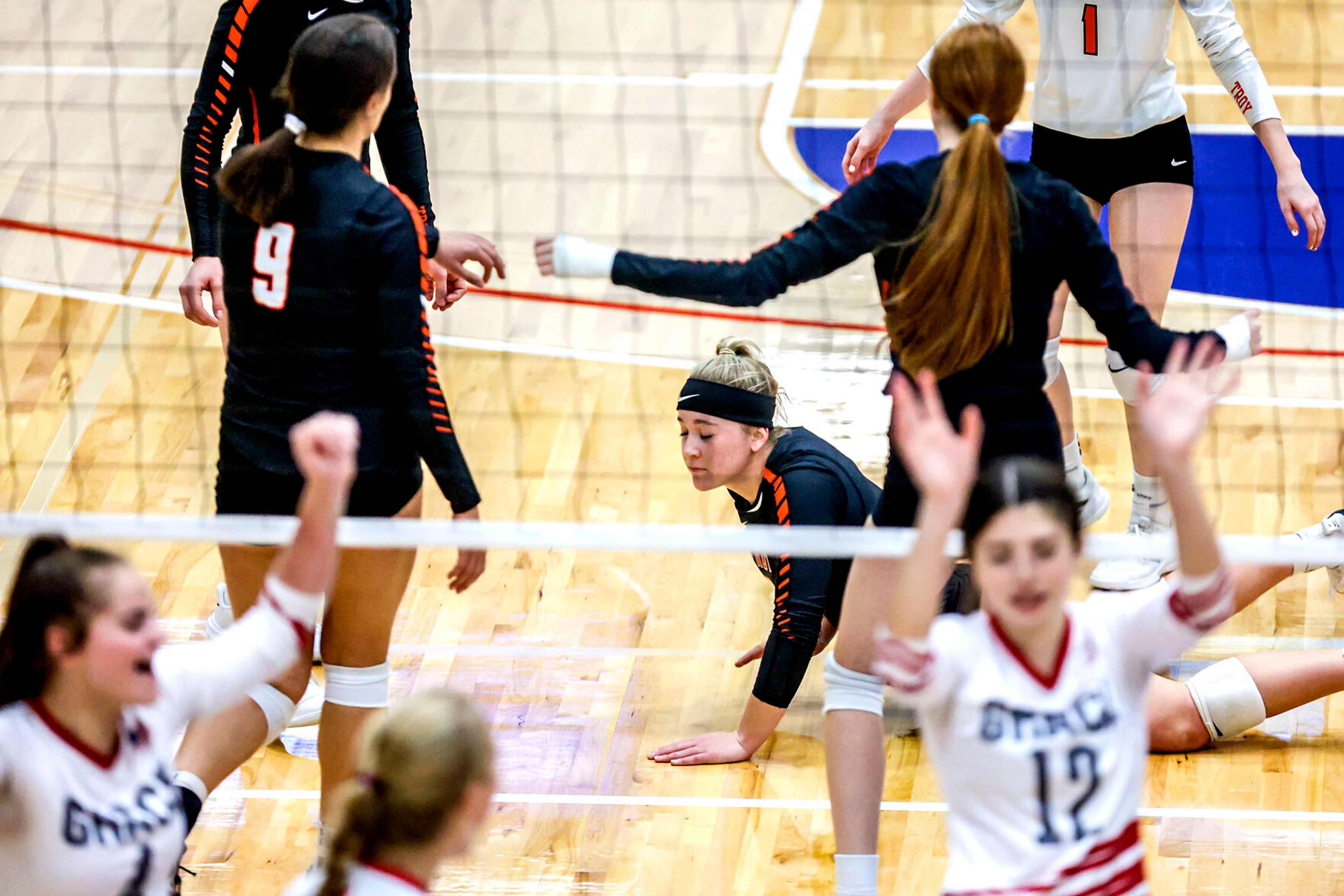 Troy outside hitter Morgan Blazzard picks herself up after a dive for a ball as Grace celebrates a point at the Lewis-Clark State College Athletic Center on Saturday. Troy defeated Grace in three sets to become the 1A DI state champions.