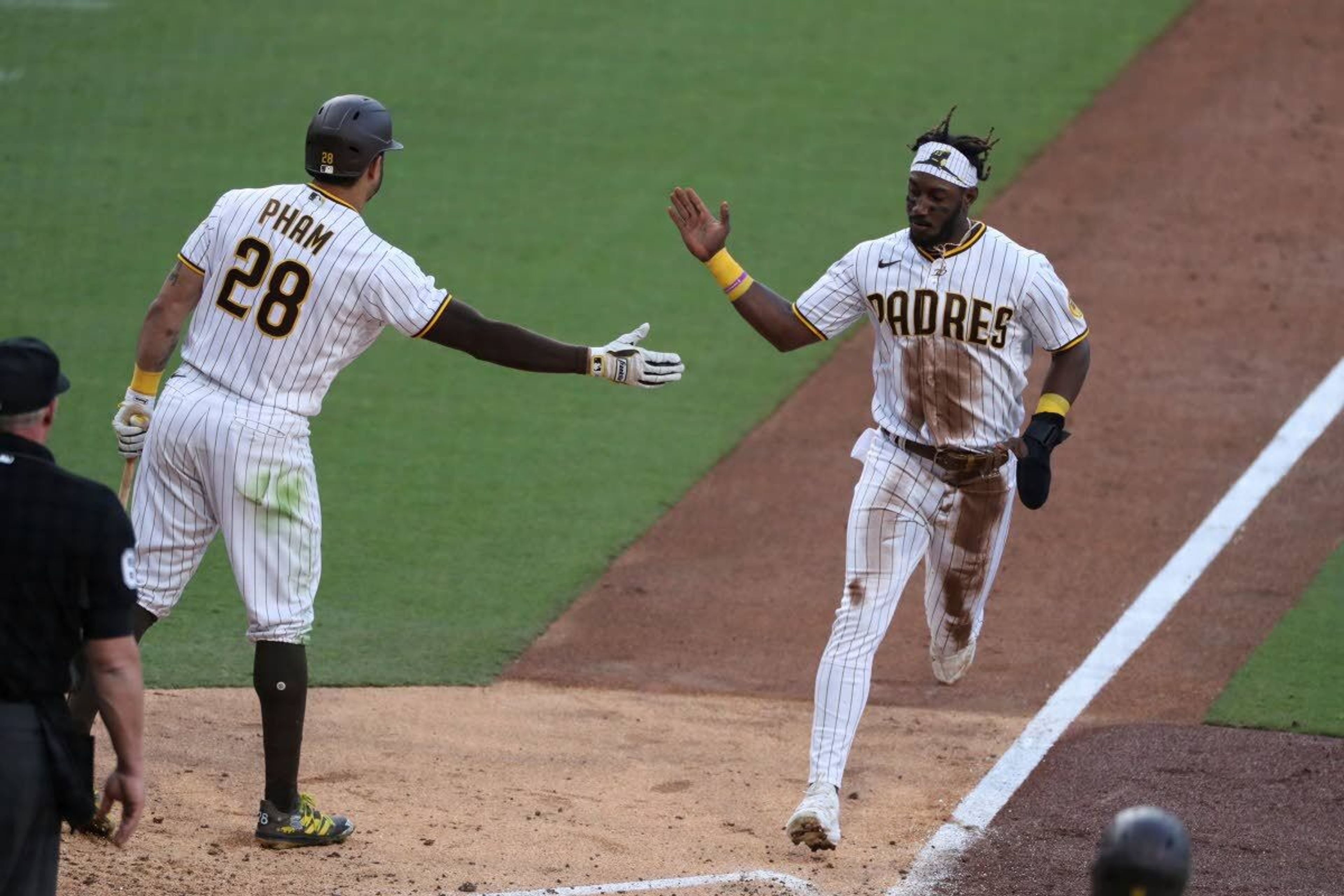 San Diego Padres' Jorge Mateo, right, is congratulated by Tommy Pham (28) on a steal of third base and scoring on a throwing error by Seattle Mariners catcher Tom Murphy during the fifth inning of a baseball game Saturday, May 22, 2021, in San Diego. (AP Photo/Derrick Tuskan)