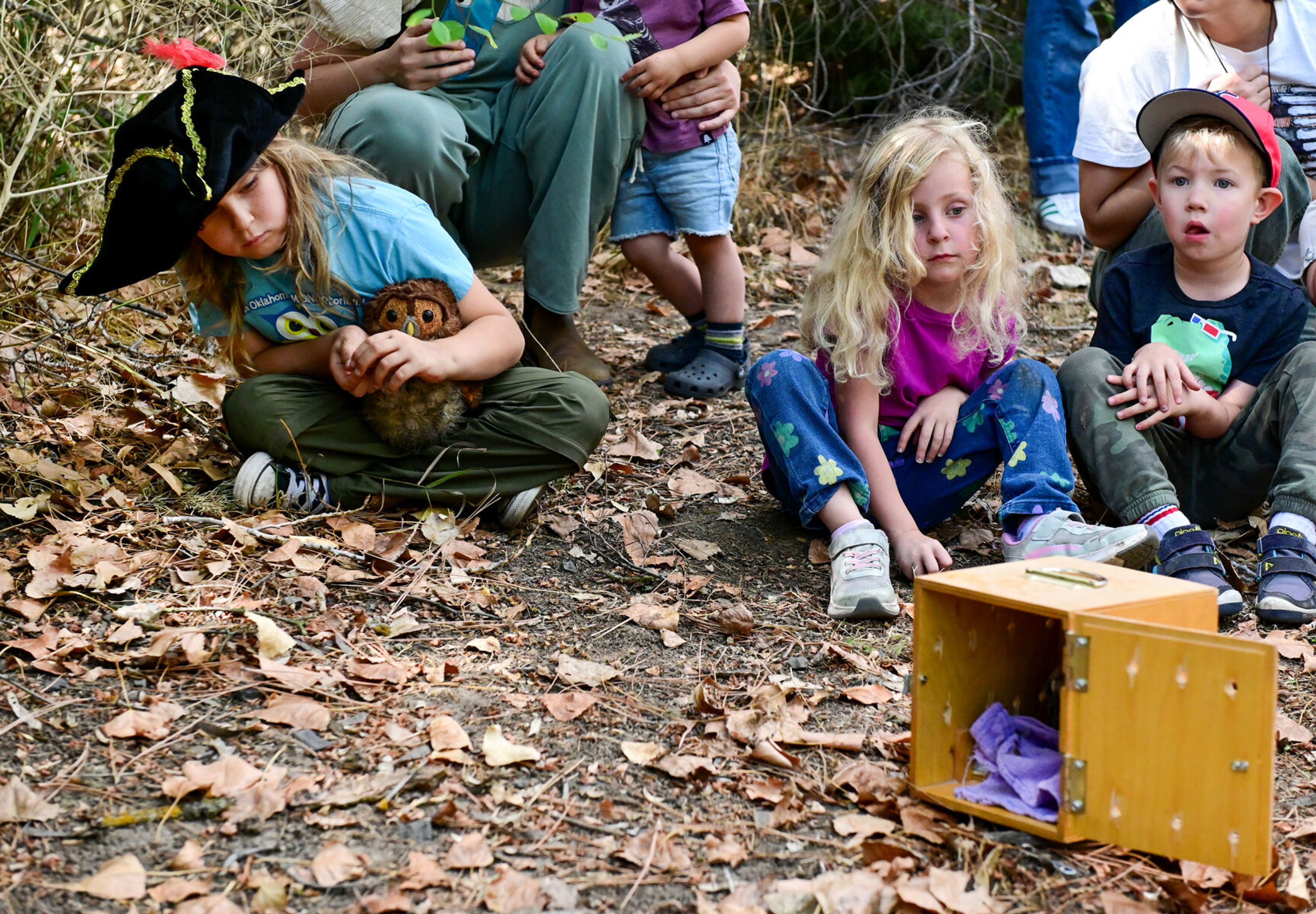 Oliver Adams, left, 8, holds a stuffed owl in his lap while leaning to get a view of the Western screech owl being released in front of students of Palouse Roots, Palouse-Clearwater Environmental Institute’s nature school, at the nature center Thursday in Moscow.