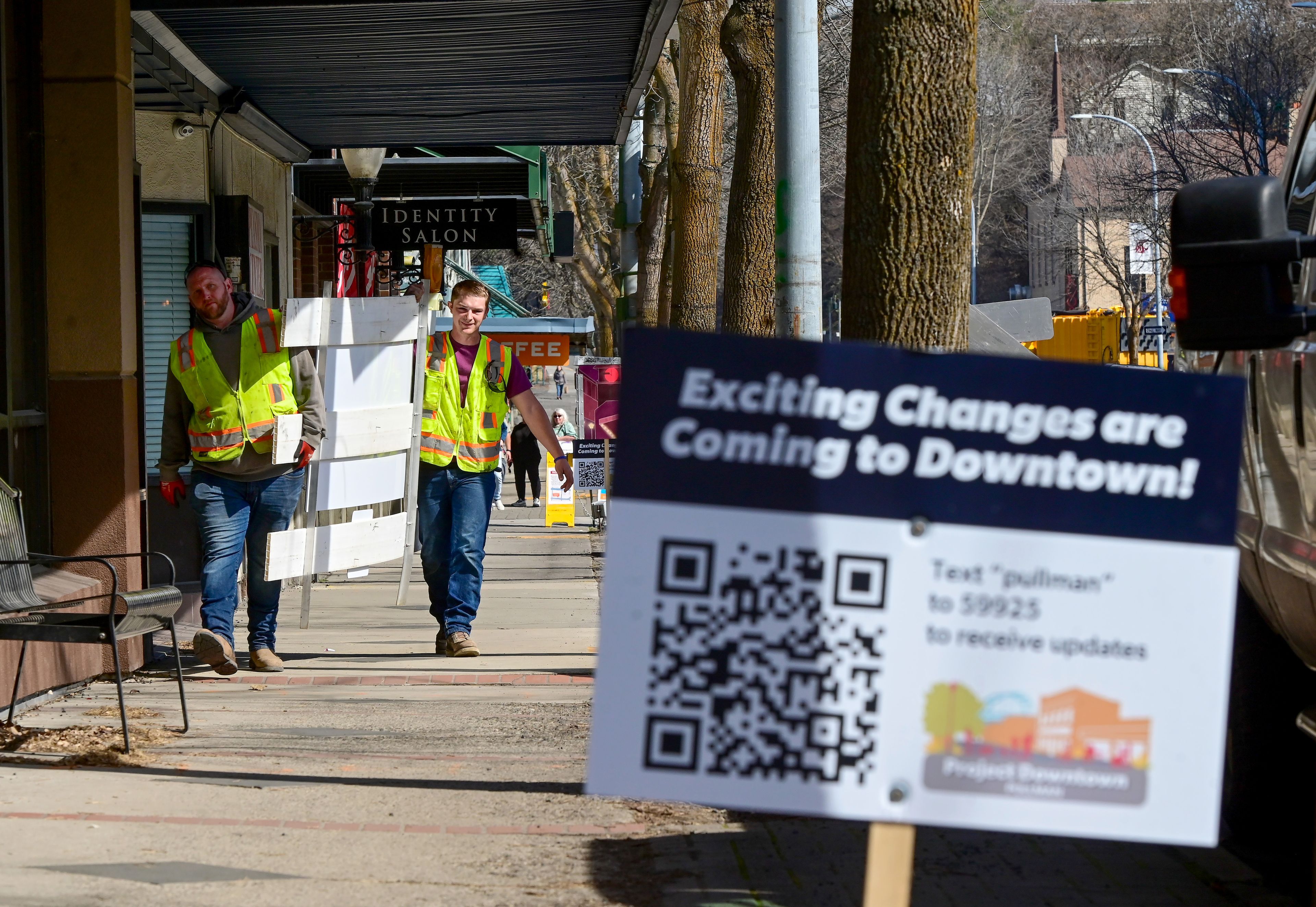 Workers with Apollo Inc on Monday carry street signs with directions to storefronts in downtown Pullman in preparation of the start of construction on Main Street.