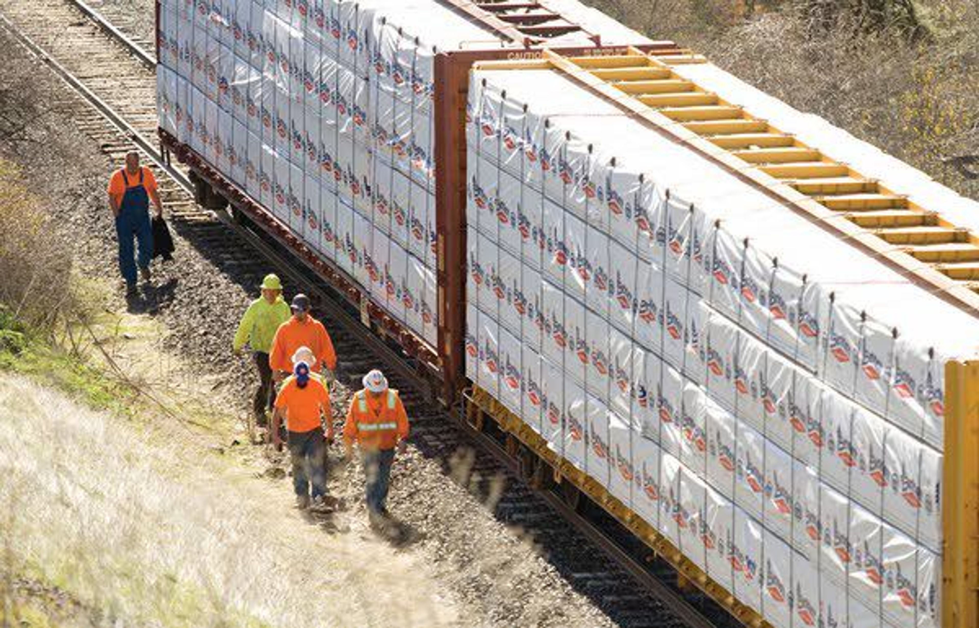 Workers from the Washington and Idaho Railway assess four derailed train cars on Tuesday about two miles north of Palouse. The railroad is planning to use large excavators to lift the cars back onto the track. The train has three cars of grain and gives gars of lumber from Bennett Lumber Products.