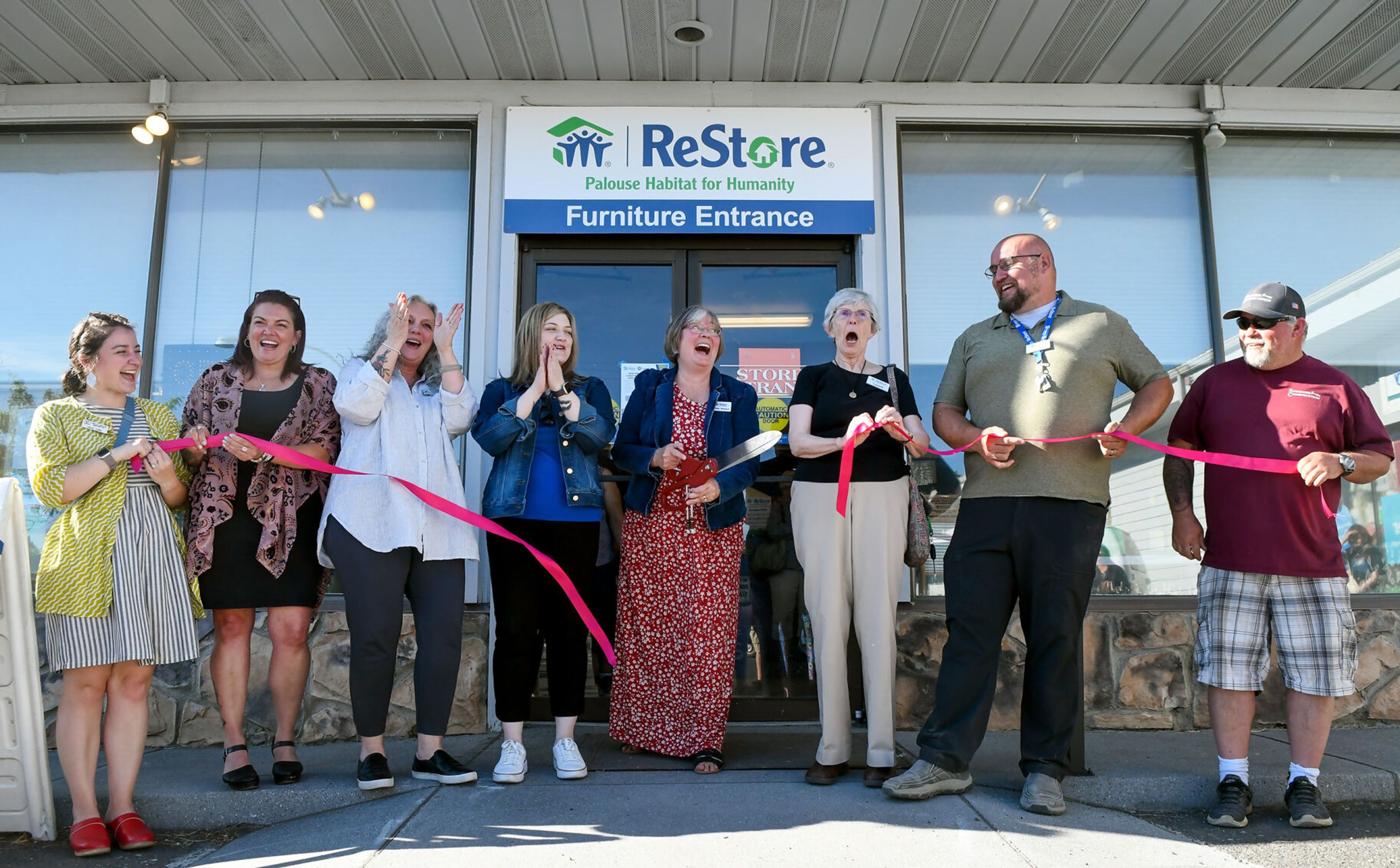 A collection of people who helped support the Palouse Habitat for Humanity ReStore’s renovations celebrate a ribbon being cut by PHFH executive director Jennifer Wallace, center, at the ReStore’s grand reopening celebration in Moscow on Thursday.