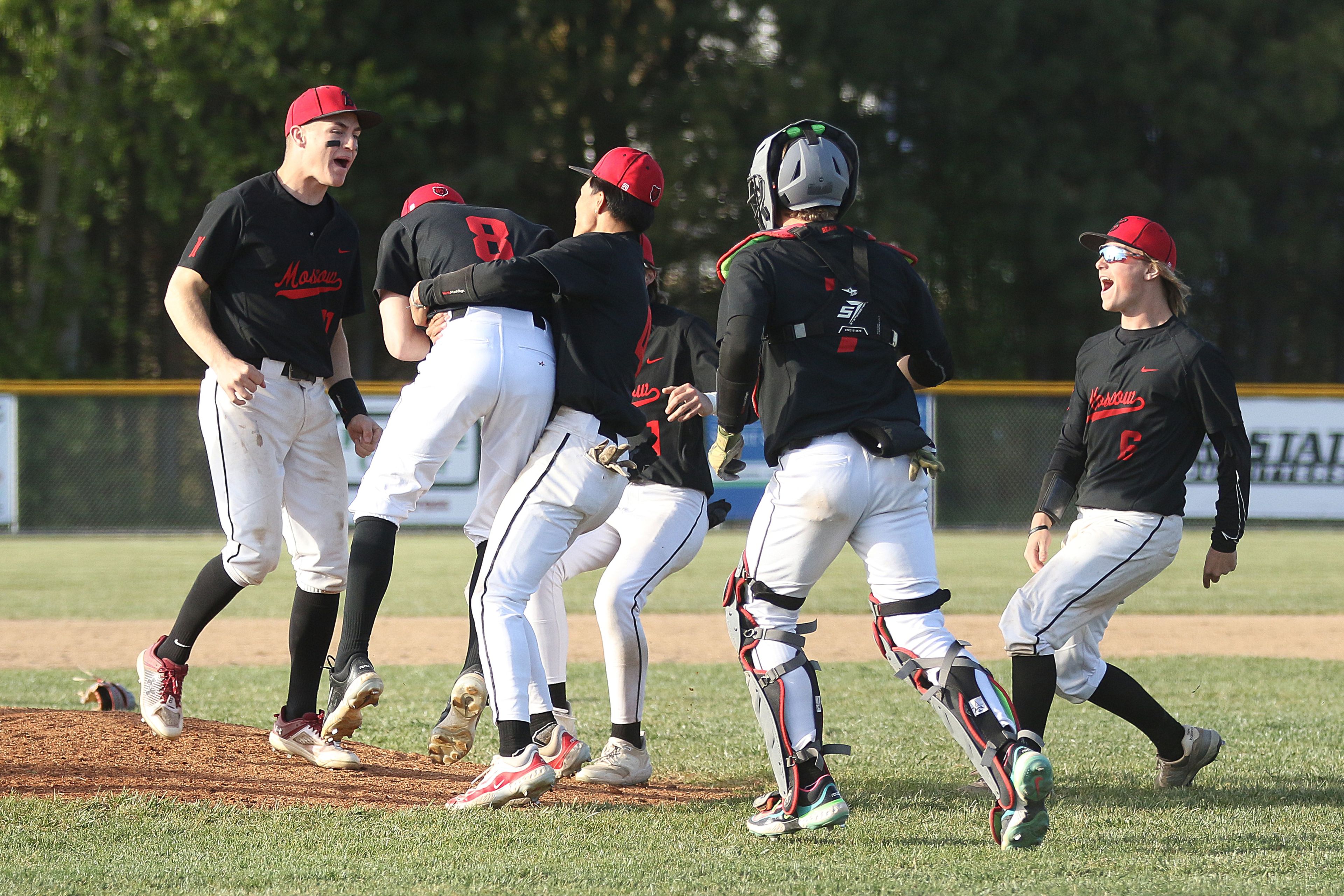 Moscow players swarm pitcher Butch Kiblen (8) after he gets the last out of an Idaho Class 4A district championship game against Sandpoint on Wednesday in Moscow.