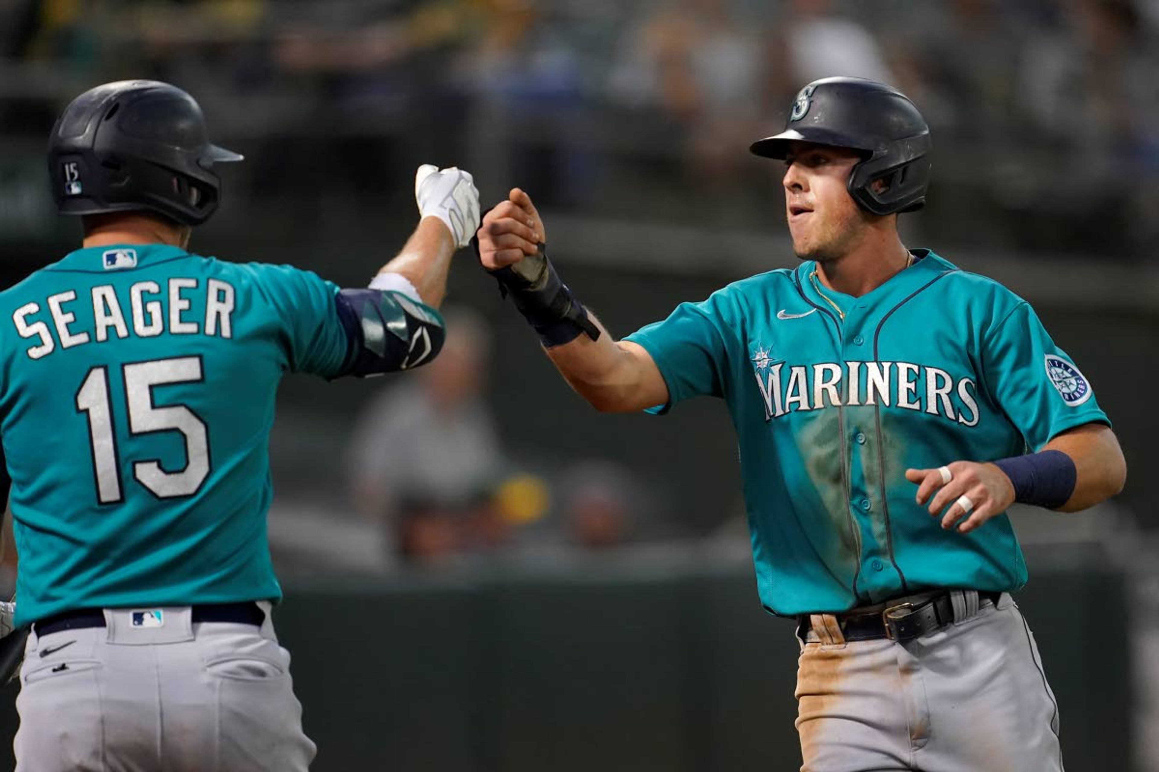 Seattle Mariners' Dylan Moore, right, is congratulated by Kyle Seager after scoring a run against the Oakland Athletics during the third inning of a baseball game in Oakland, Calif., Monday, Sept. 20, 2021. (AP Photo/Jeff Chiu)