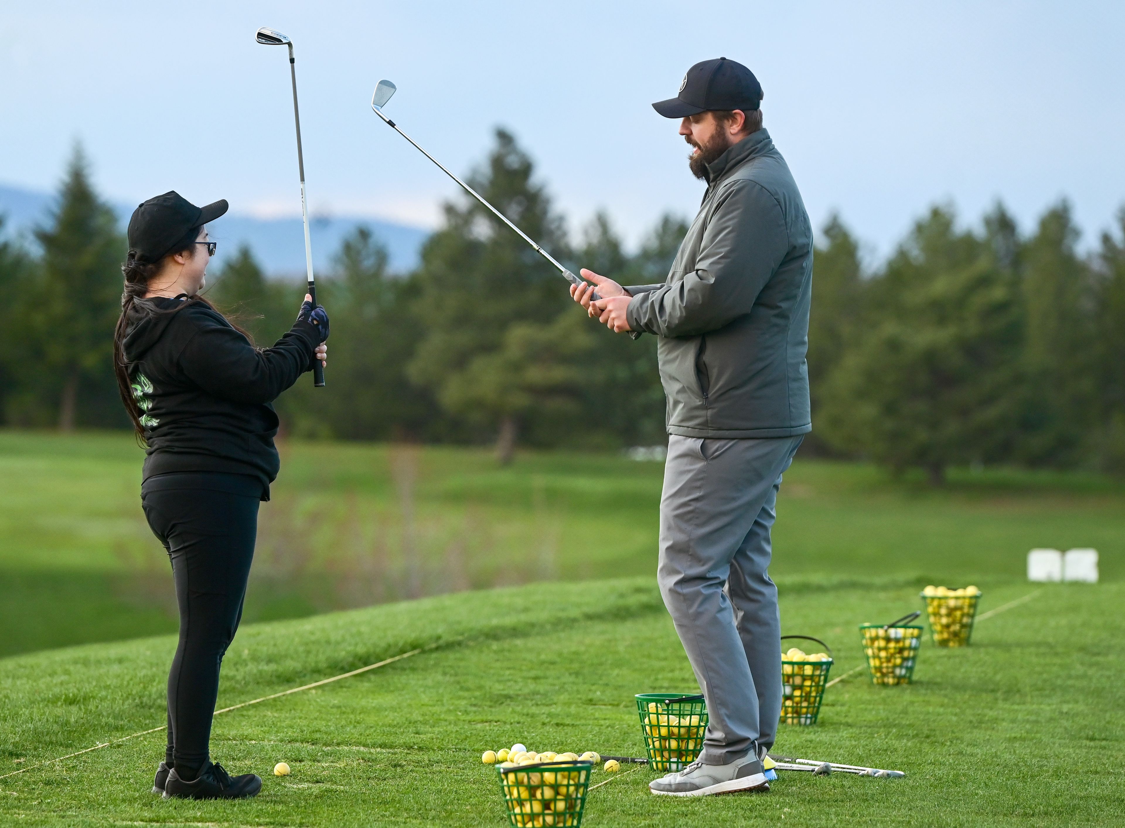 Liddy Kang, of Moscow, raises her club to adjust her grip under the instruction of Michael Wagner, right, head golf professional at the University of Idaho Golf Course, during a women’s class in Moscow on Tuesday.