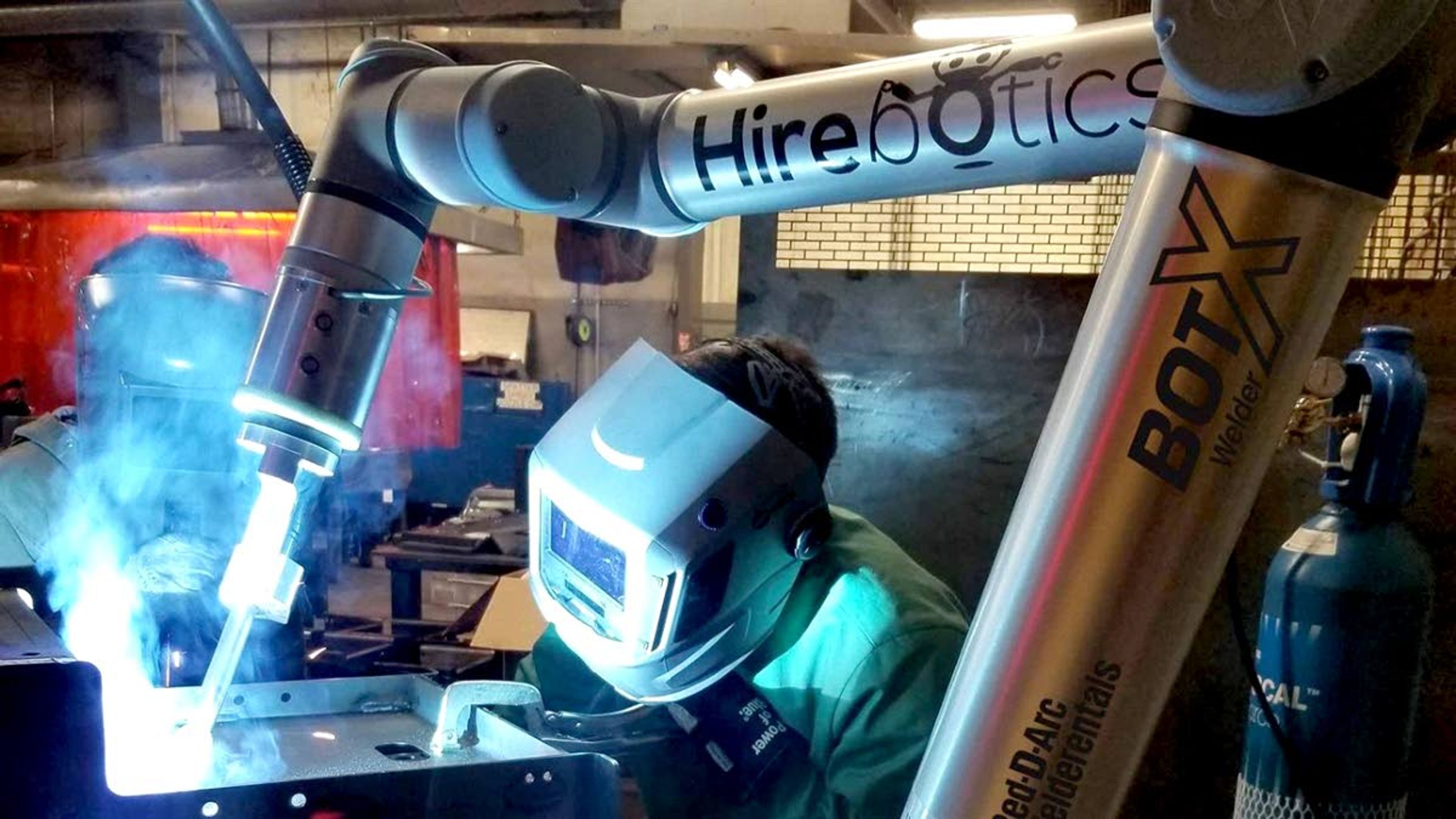 A robot welding machine works in March with human welders at PMI, a steel fabrication factory in Bloomer, Wis. Some experts see automation accelerating in the pandemic as workers and customers avoid human interaction.