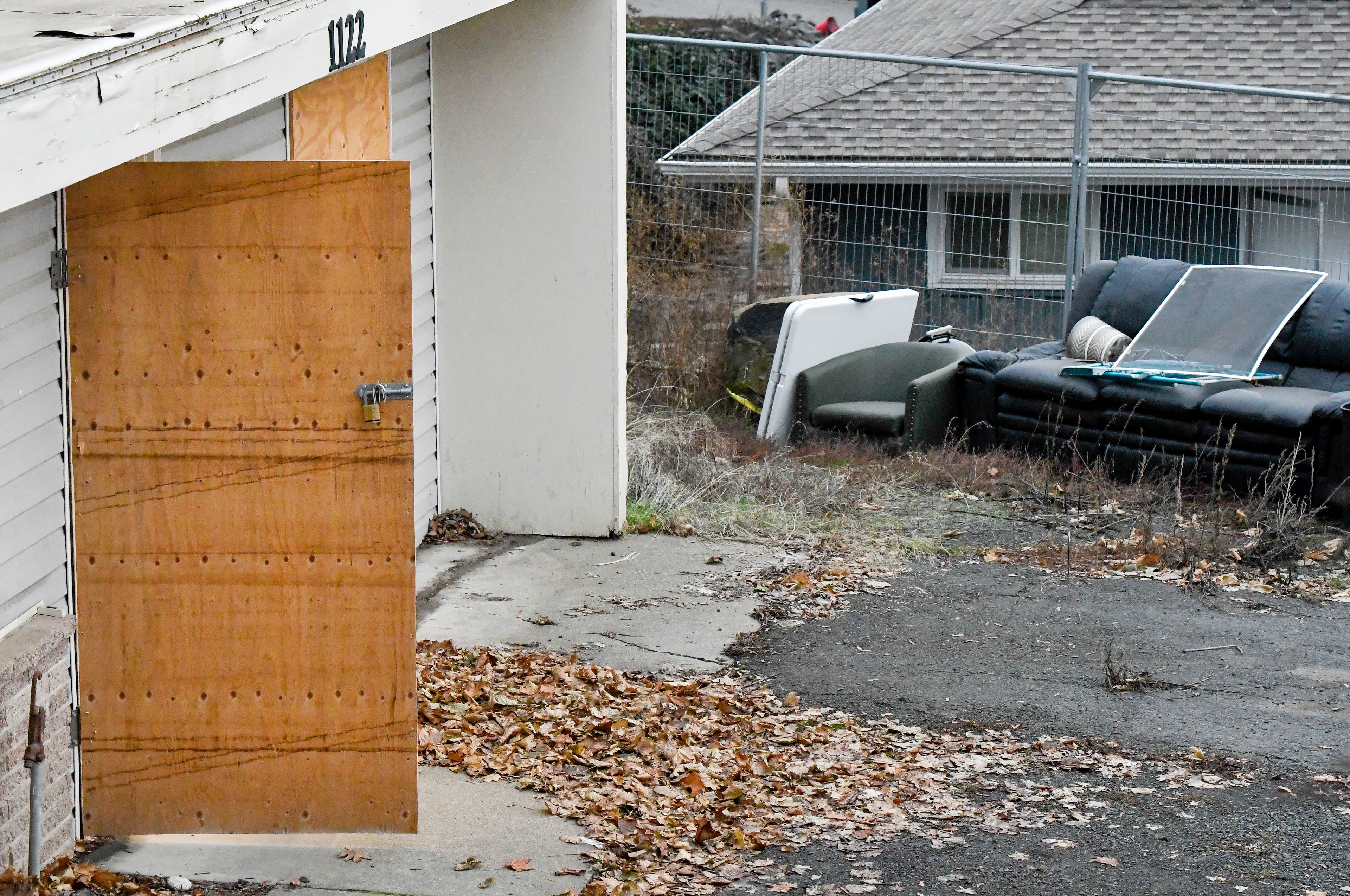 A board used to cover the front door of the King Road house where four University of Idaho students were killed last year swings open and closed from a breeze in Moscow on Thursday. The college announced that the defense team for suspect Bryan Kohberger will be given access to the house Thursday and Friday as it prepares its case for a trial.