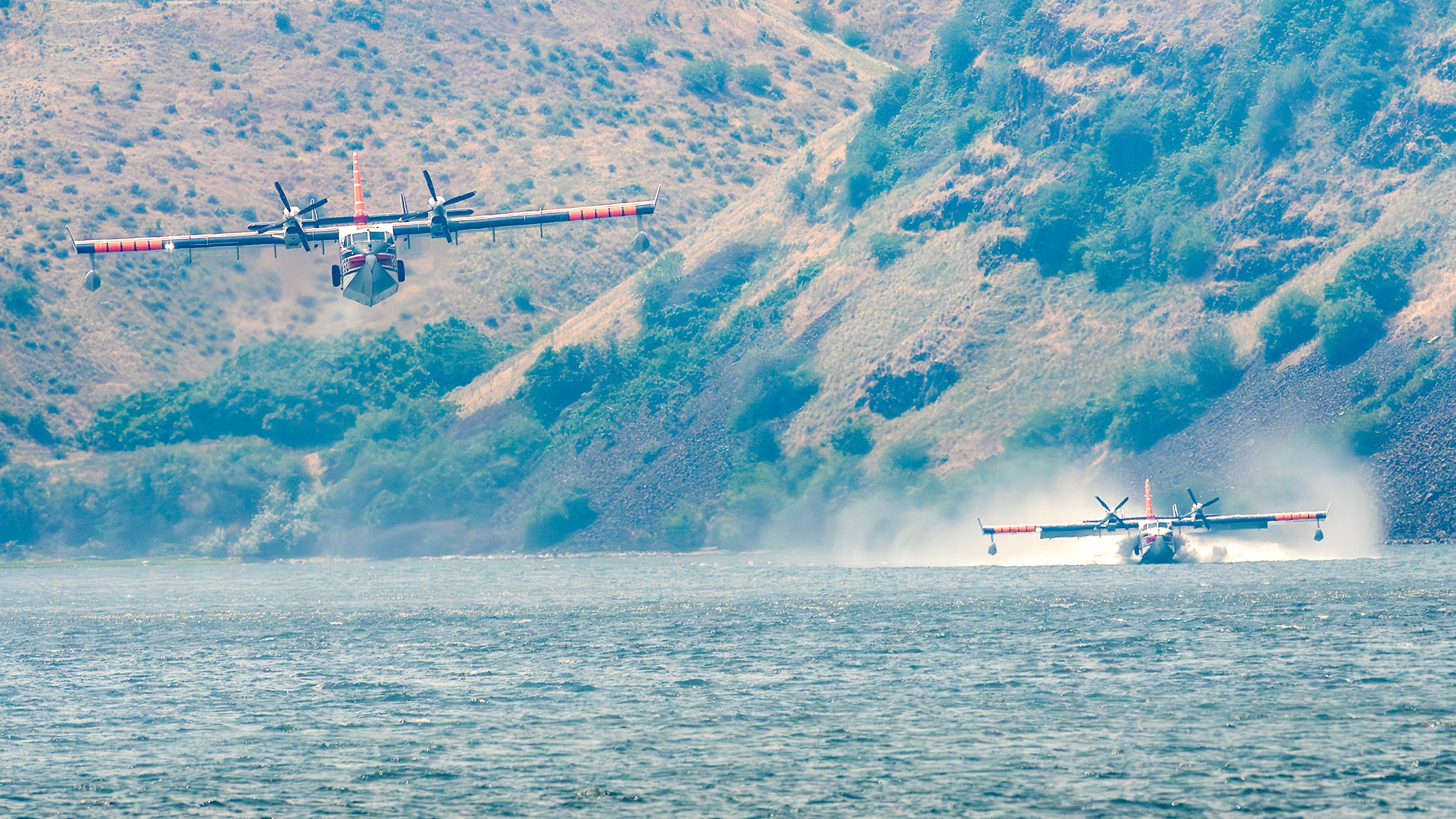 Drop planes fill up with water in the Snake River before dumping their load on a fire burning along the hills nearby Nisqually John Landing off of Wawawai Road on Friday.