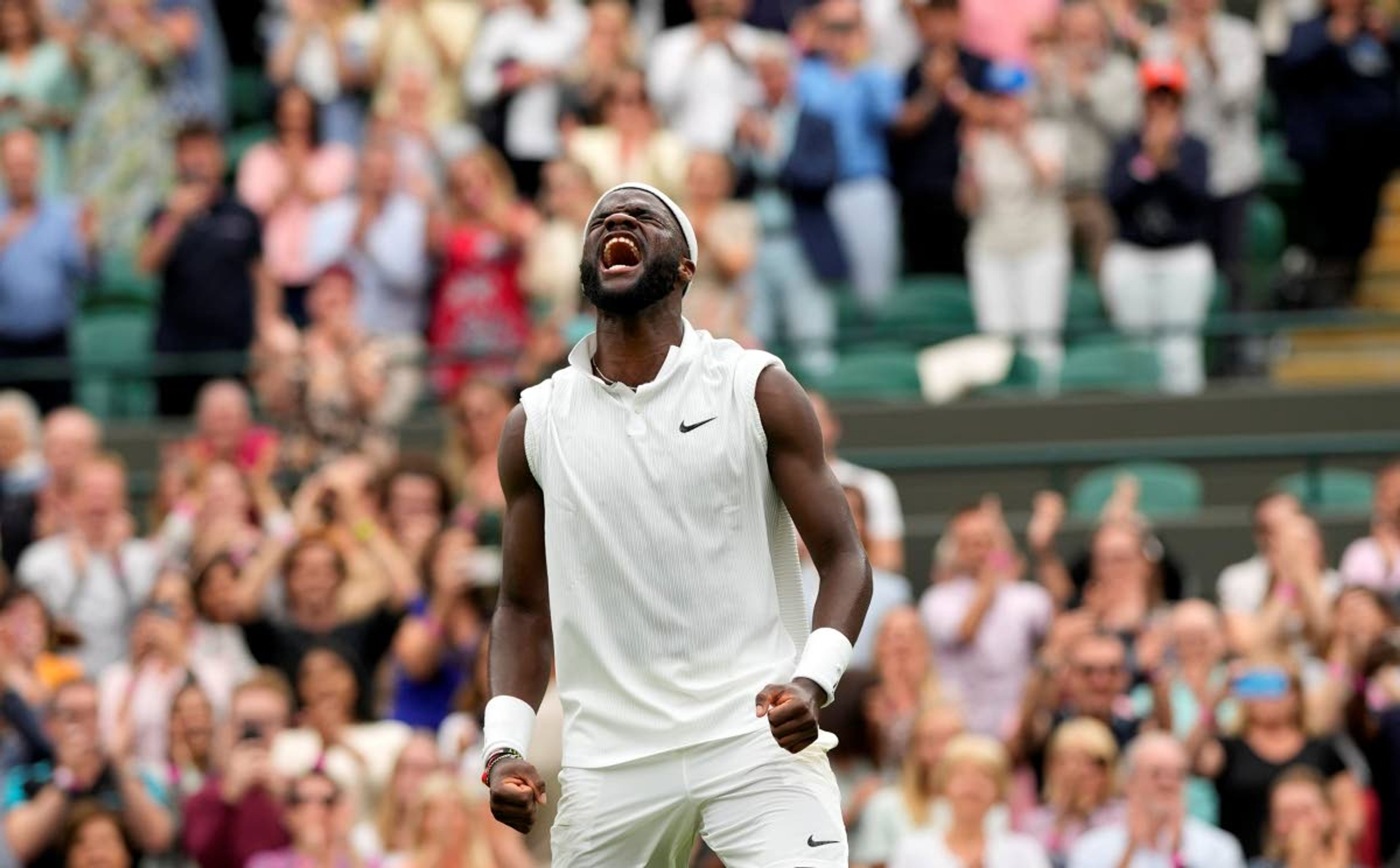 Frances Tiafoe of the US celebrates after winning the men's singles match against Stefanos Tsitsipas of Greece on day one of the Wimbledon Tennis Championships in London, Monday June 28, 2021. (AP Photo/Alastair Grant)