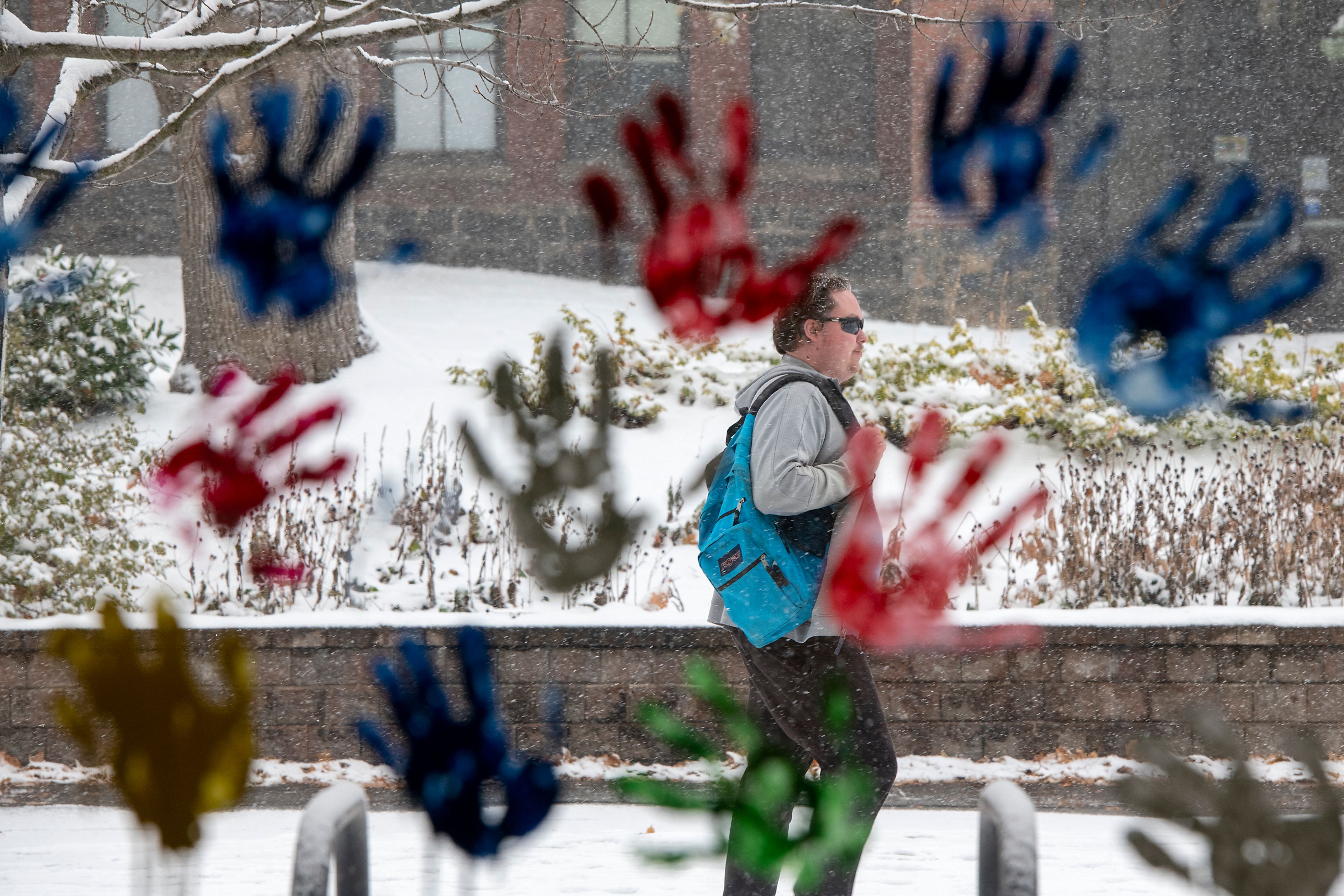 A University of Idaho student walks through the snow as class resumes Monday on the Moscow campus. In the foreground are multi-colored handprints on a window of the Idaho Student Union Building.