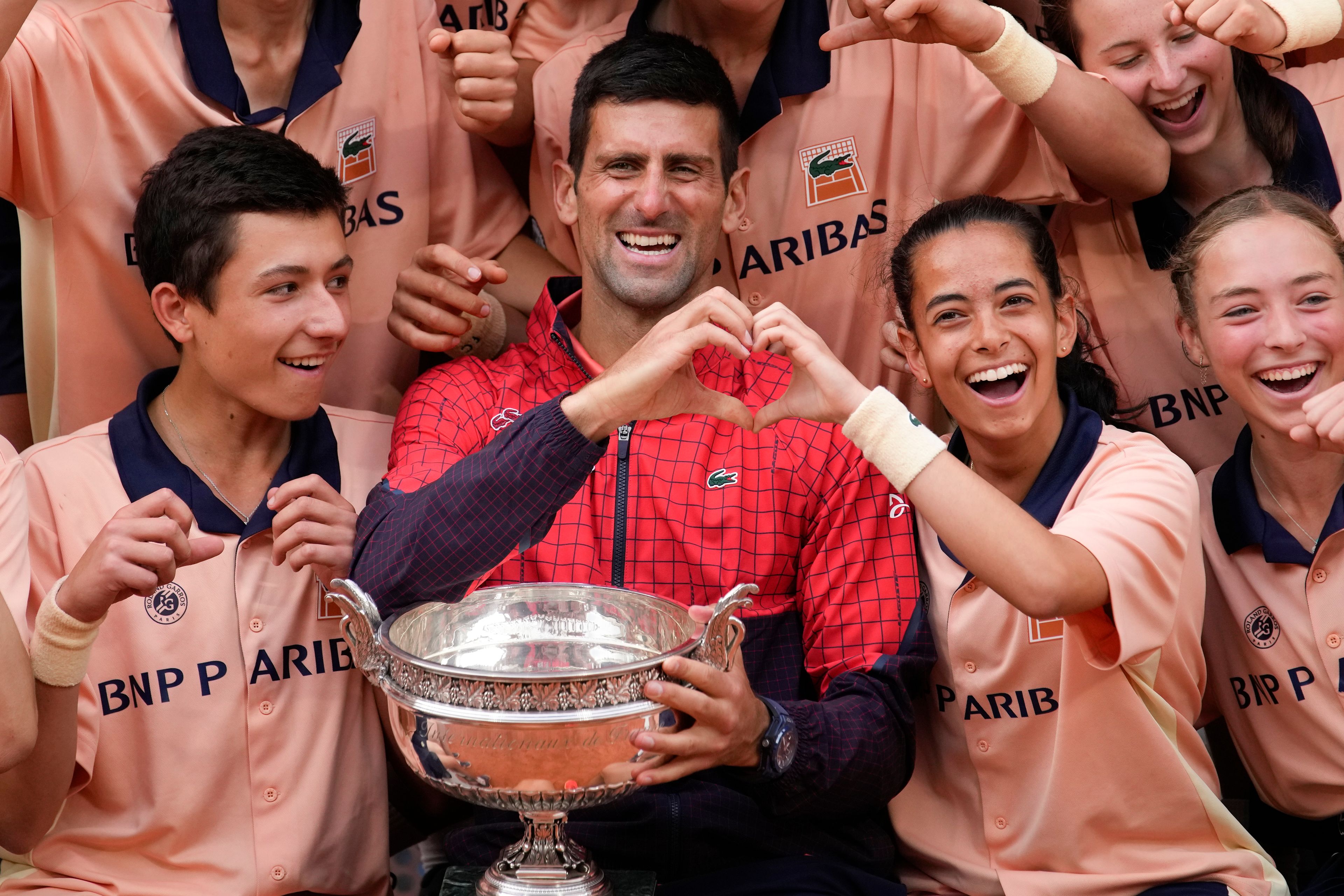 Serbia's Novak Djokovic poses with ball girls and boys as he celebrates winning the men's singles final match of the French Open tennis tournament against Norway's Casper Ruud in three sets, 7-6, (7-1), 6-3, 7-5, at the Roland Garros stadium in Paris, Sunday, June 11, 2023. Djokovic won his record 23rd Grand Slam singles title, breaking a tie with Rafael Nadal for the most by a man. (AP Photo/Christophe Ena)