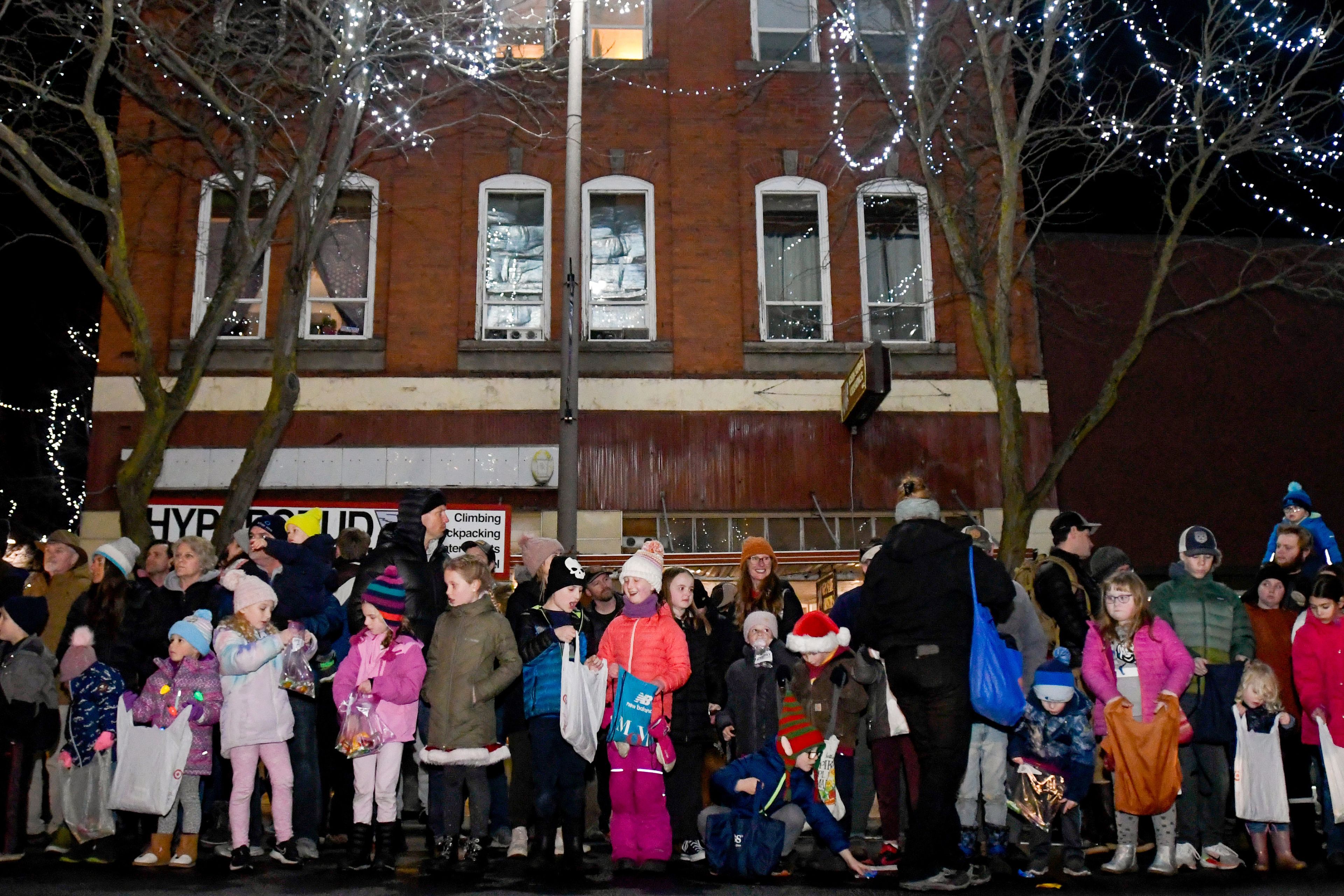 Children turn to each other to show off their candy being collected during the Light Up the Season parade on Thursday.