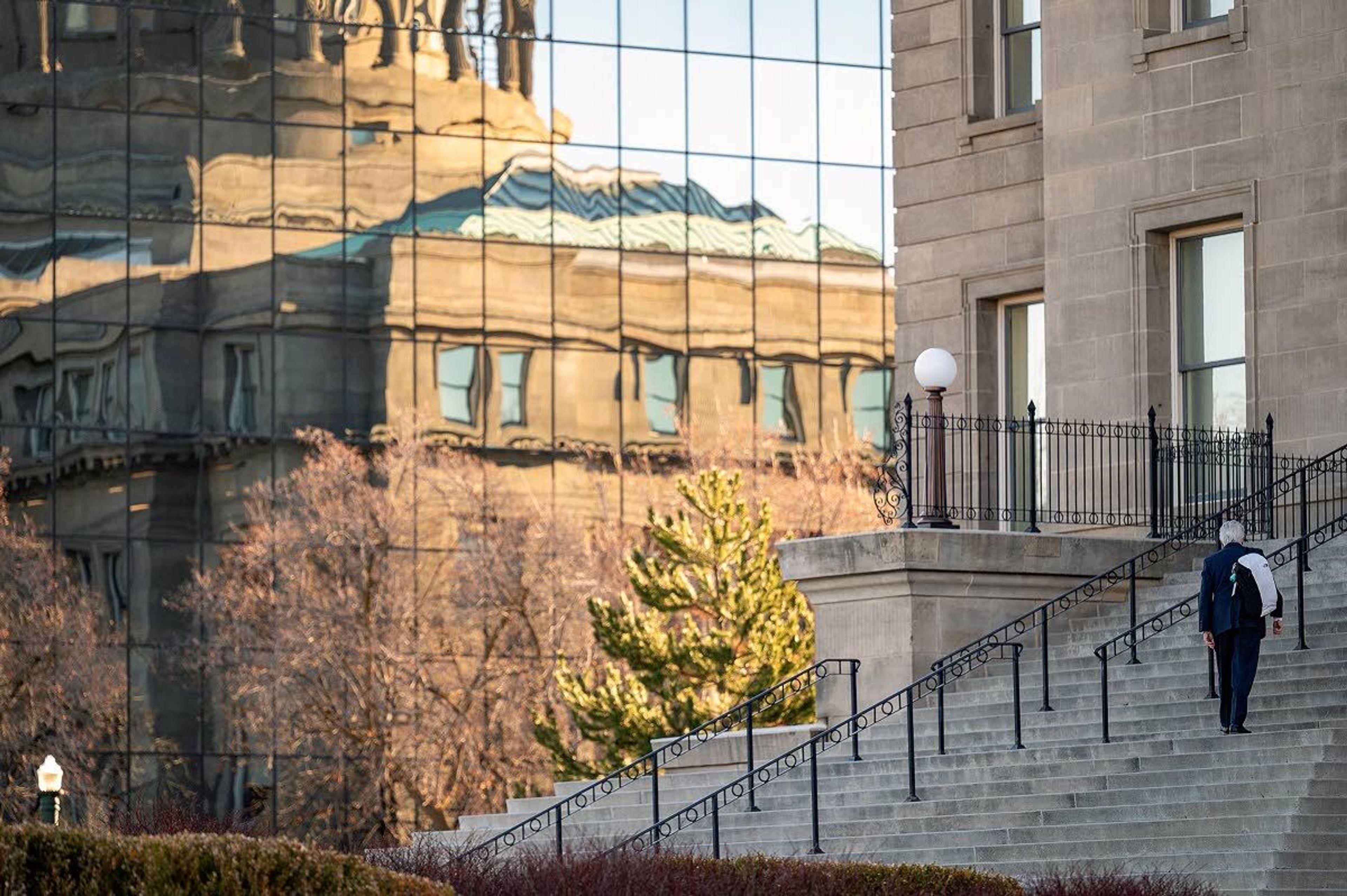 The north end of the Idaho Capitol is reflected in the windows of the Joe R. Williams Building across West State Street as a man enters the west end of the building earlier this month in Boise.