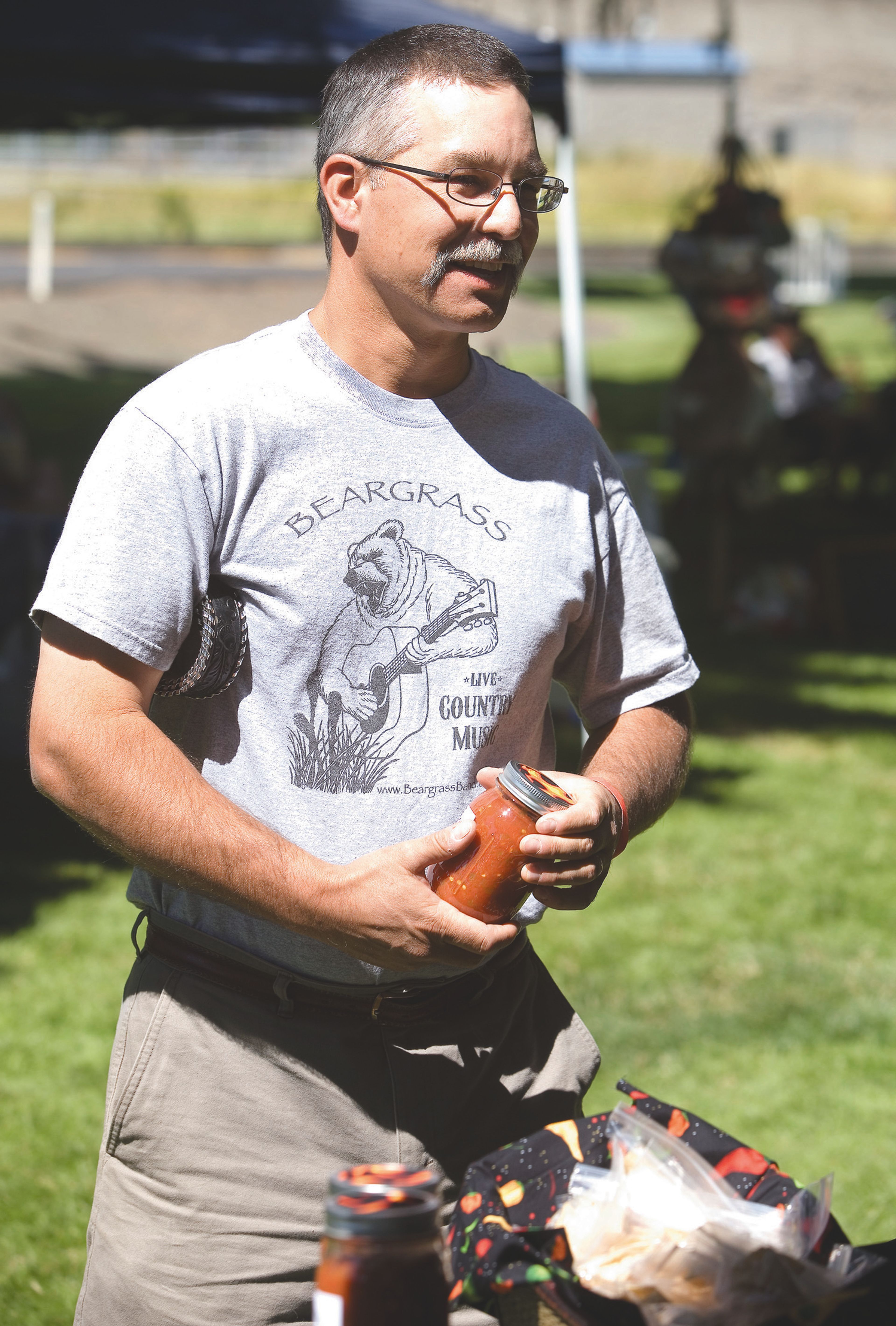 Shayne Watkins, of Deary, buys a jar of salsa from Nick and Nancy Whitesell, not seen, during the Palouse Music Festival and pig roast July 28, 2012, at Hayton-Greene Park in Palouse.