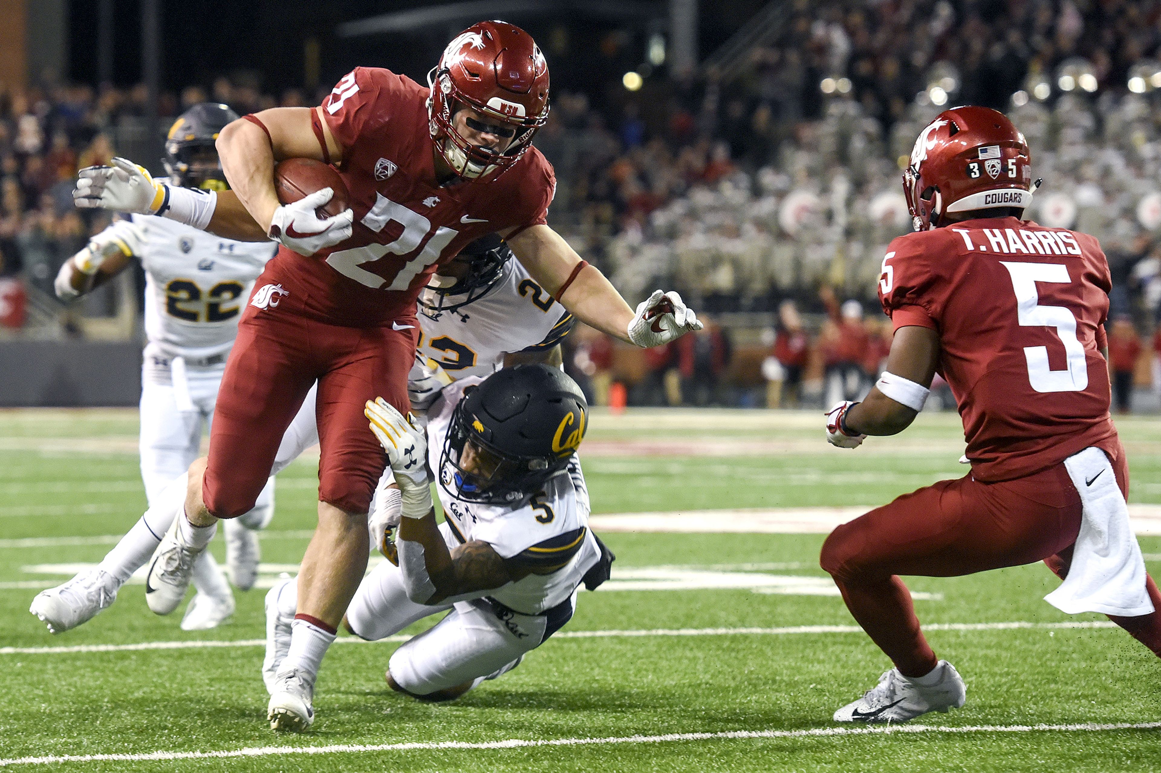 Washington State running back Max Borghi (21) breaks through a tackle attempt by California linebacker Malik Psalms (23) and safety Trey Turner III (5) during the second quarter of a PAC-12 Conference game Nov. 3 at Martin Stadium in Pullman.