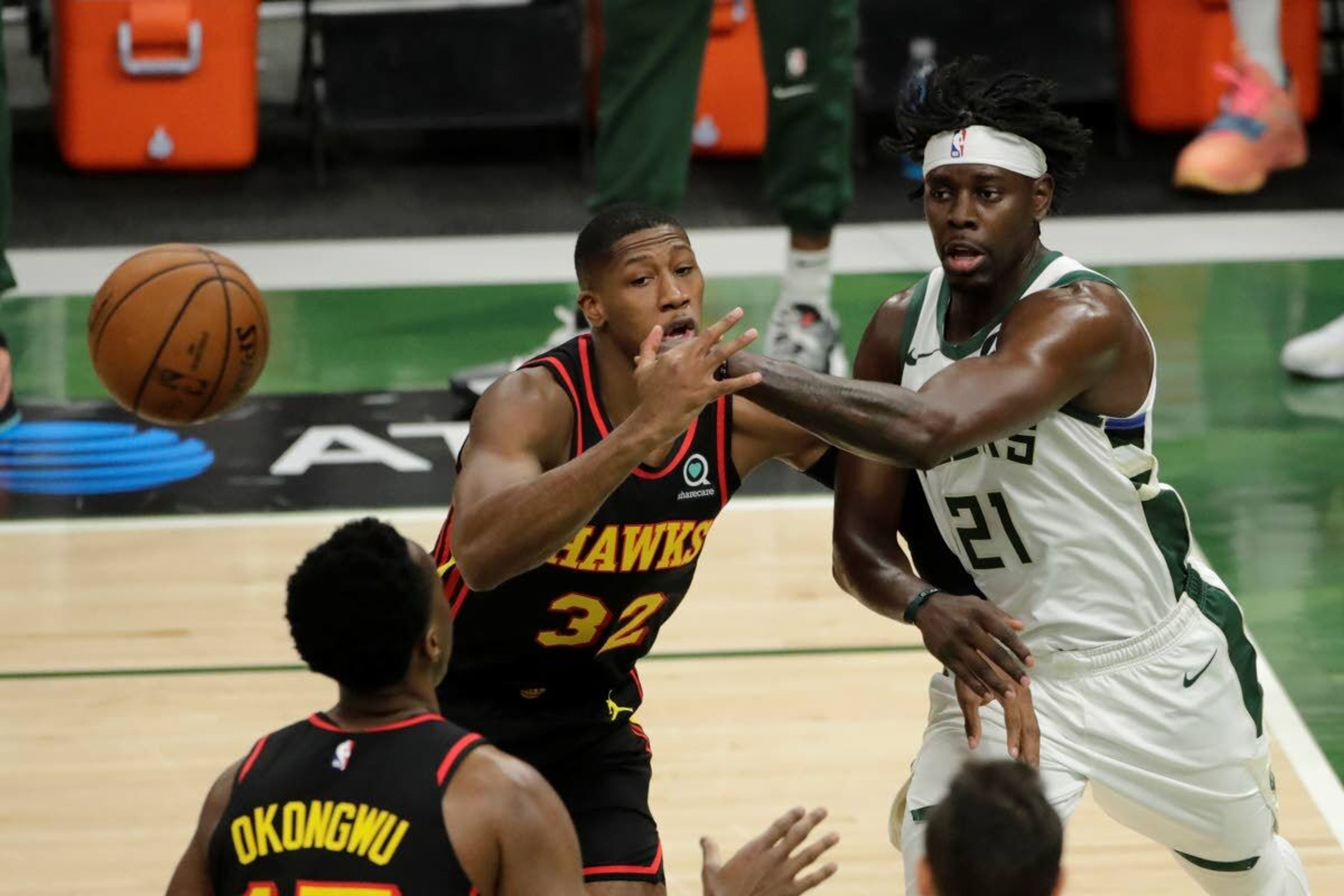 Milwaukee Bucks' Jrue Holiday, right, passes the ball past Atlanta Hawks' Kris Dunn, left, during the first half of Game 5 of the NBA Eastern Conference Finals Thursday, July 1, 2021, in Milwaukee. (AP Photo/Aaron Gash)