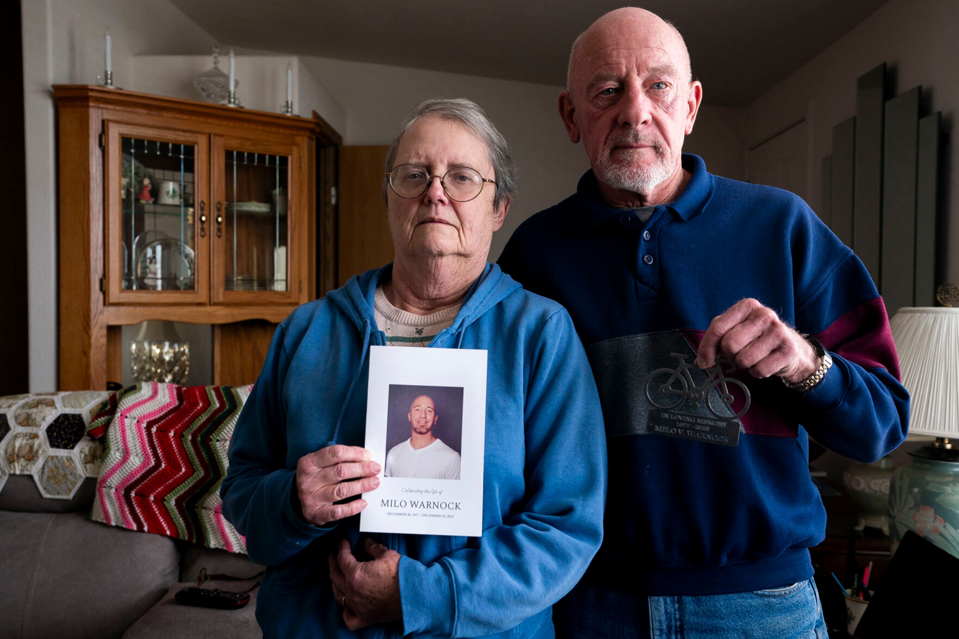 Kathy and Mike Warnock hold a photo and sheet metal memorial plaque dedicated to their son Milo Warnock inside their Clarkston home. Milo Warnock was killed in prison after being sentenced to two years for a DUI.