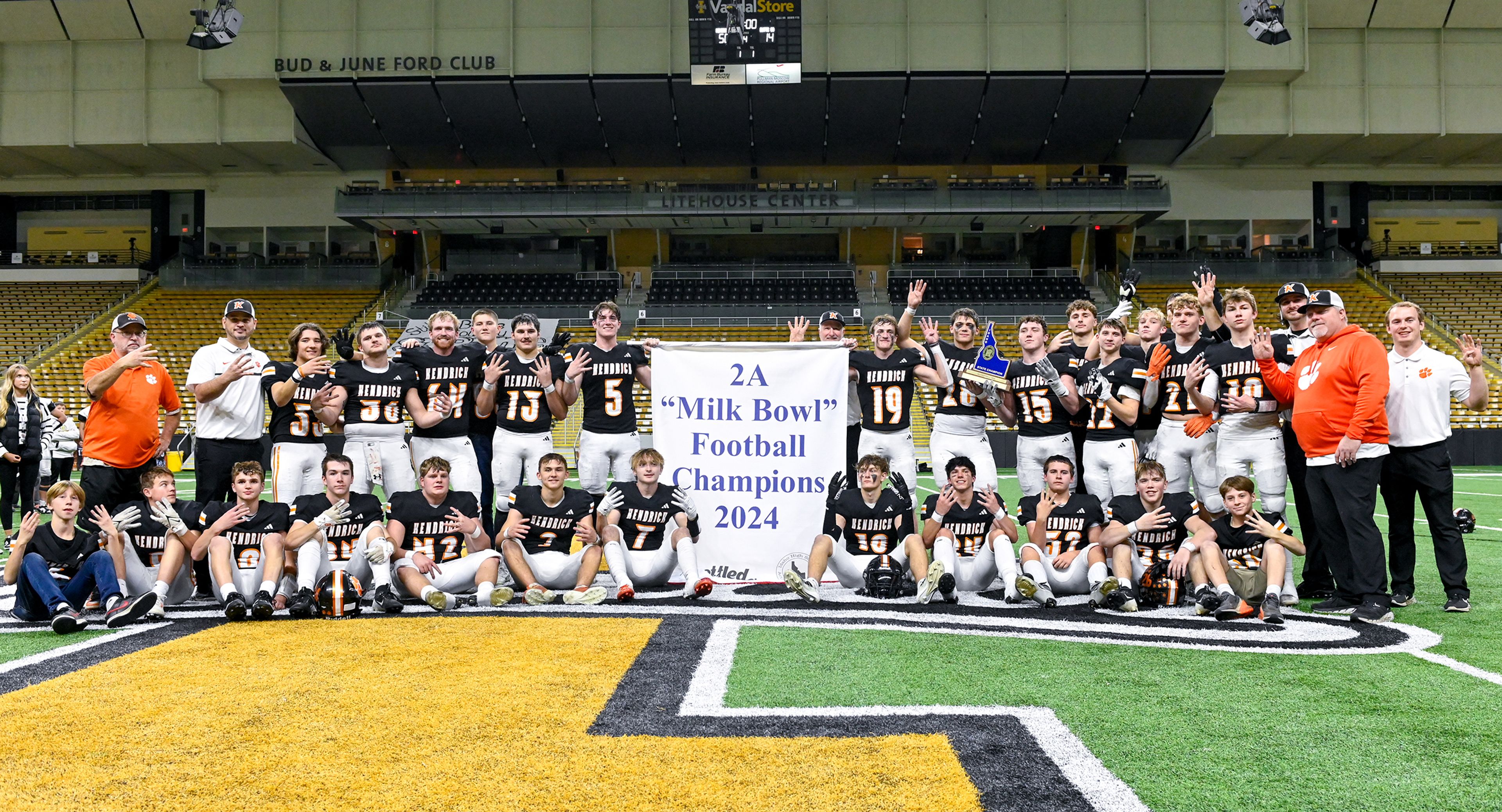 Kendrick players and coaches pose with a trophy and banner celebrating their Idaho Class 2A state championship win over Butte County at the P1FCU Kibbie Dome in Moscow.