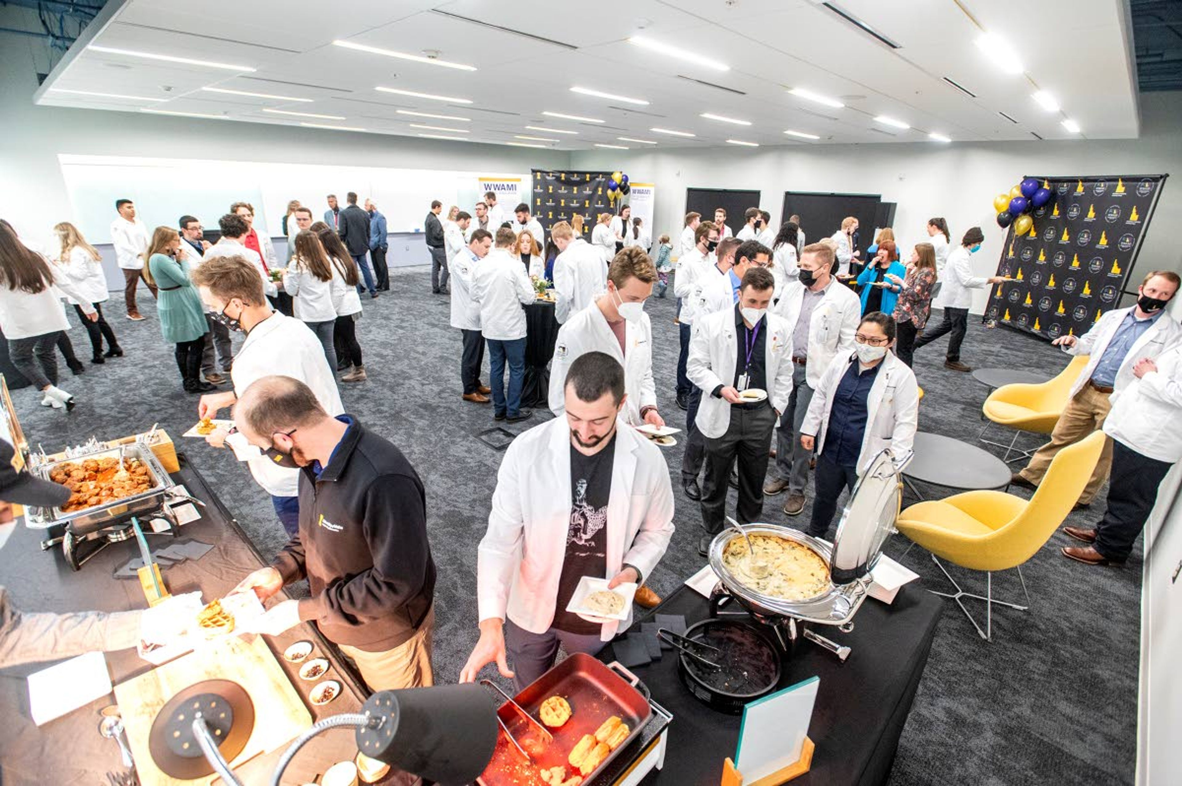 Medical students and University of Idaho staff dish plates of food and mingle.