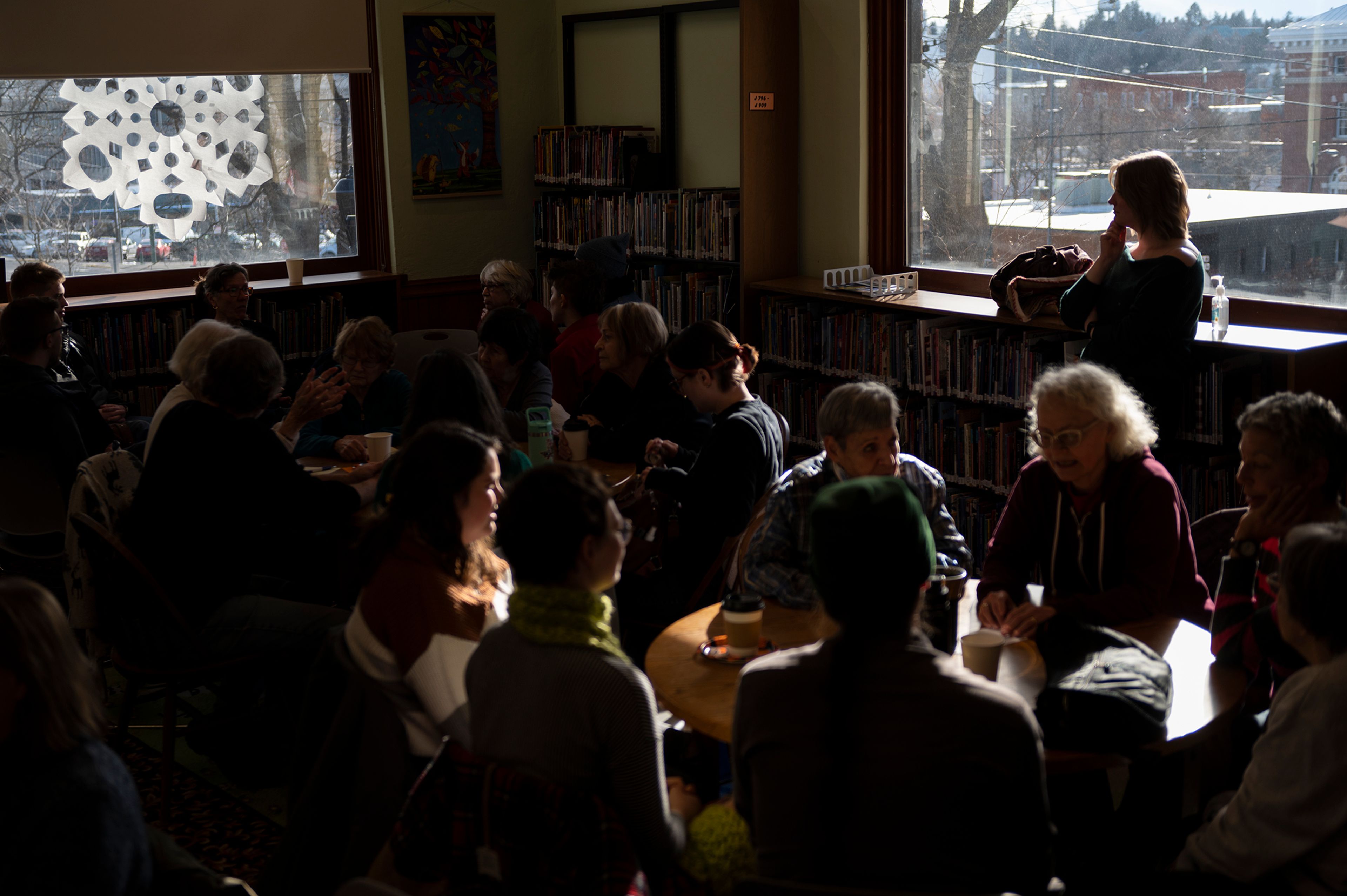 Amber Ziegler stands at the back of the room as small groups discuss death during a Death Café at the Moscow Public Library on Tuesday.