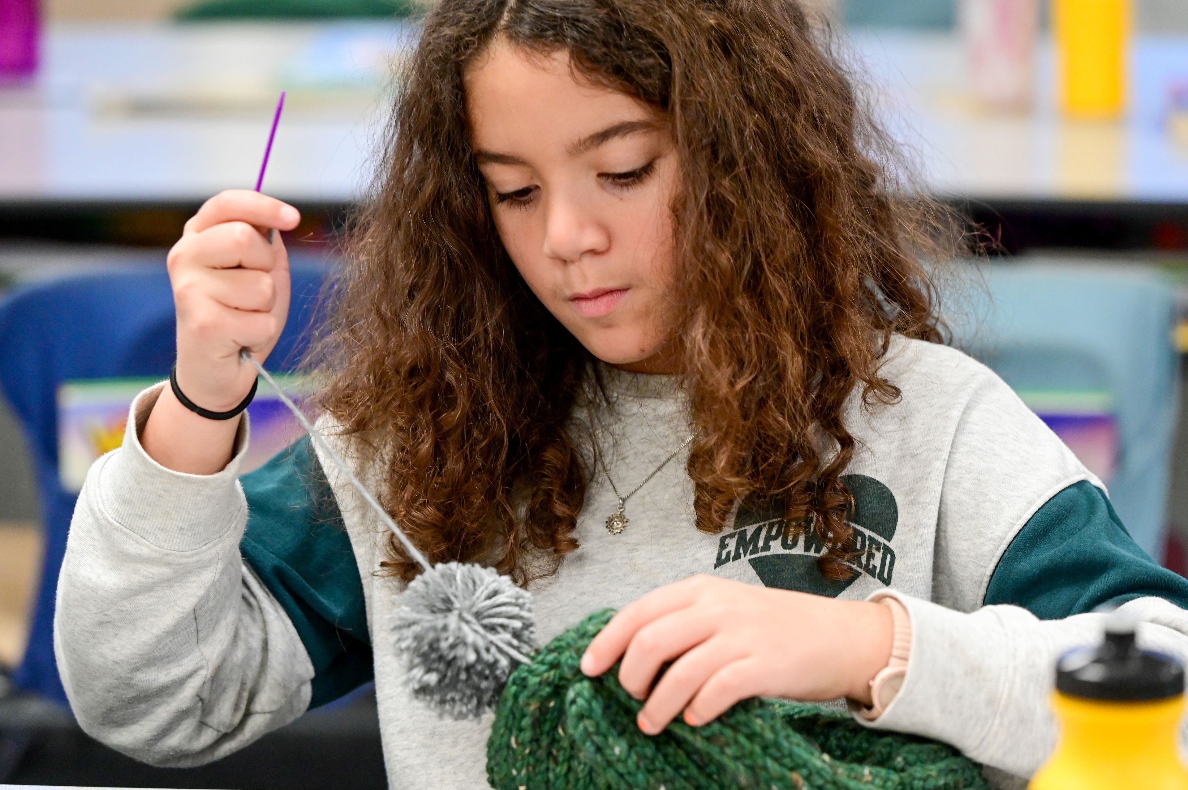 Fourth-grader Ruth Udekwu secures a pom-pom on the top of a knitted hat at Lena Whitmore Elementary School in Moscow on Monday.