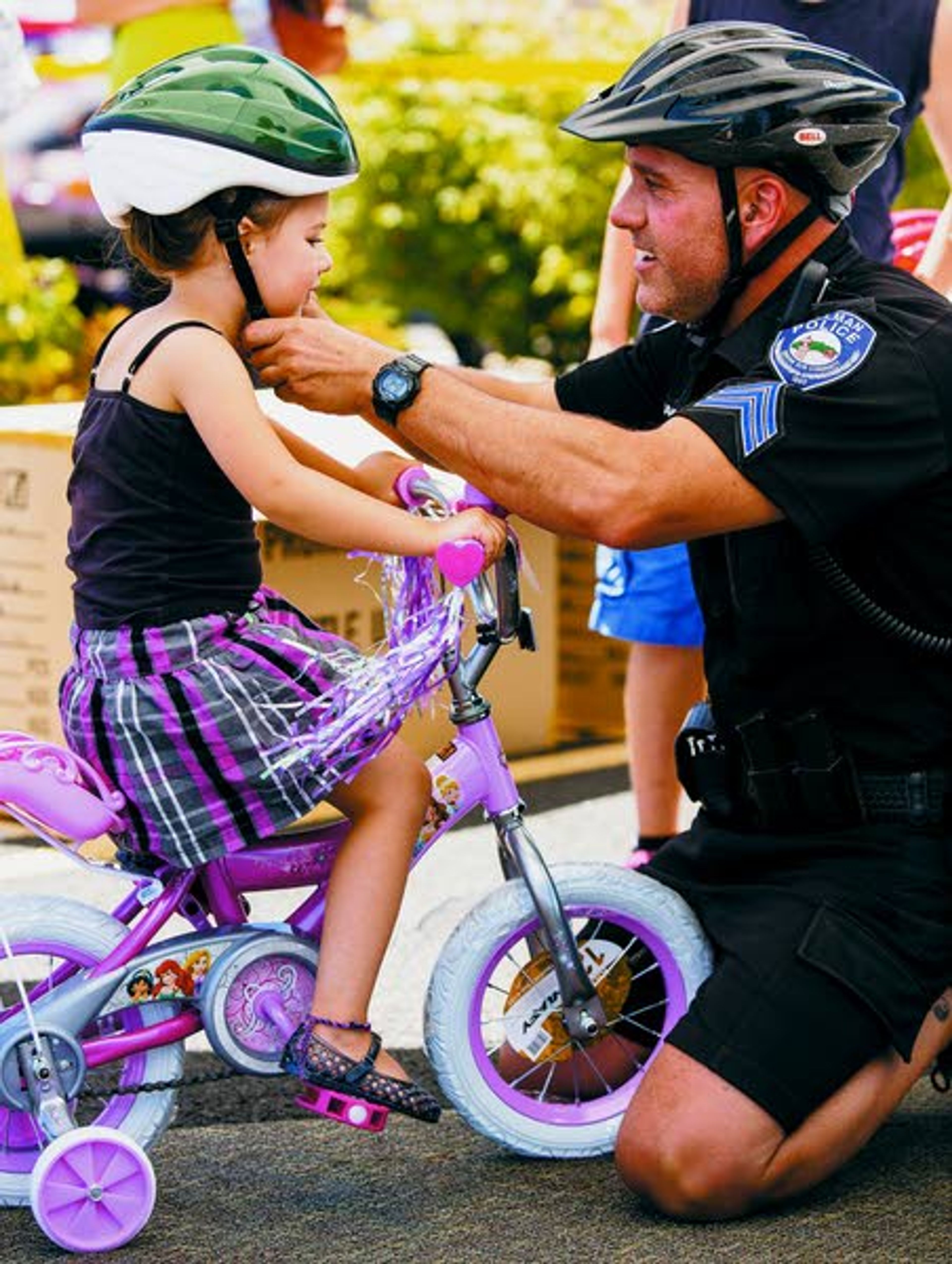 Detective Sgt. Dan Hargraves, right, fits a helmet on Grayson VanCuren, 3, of Pullman, during the first Pullman Police Department Bike Rodeo on Saturday, July 26, 2014, at the Wal-Mart in Pullman. The PPD plans to make this an annual event.