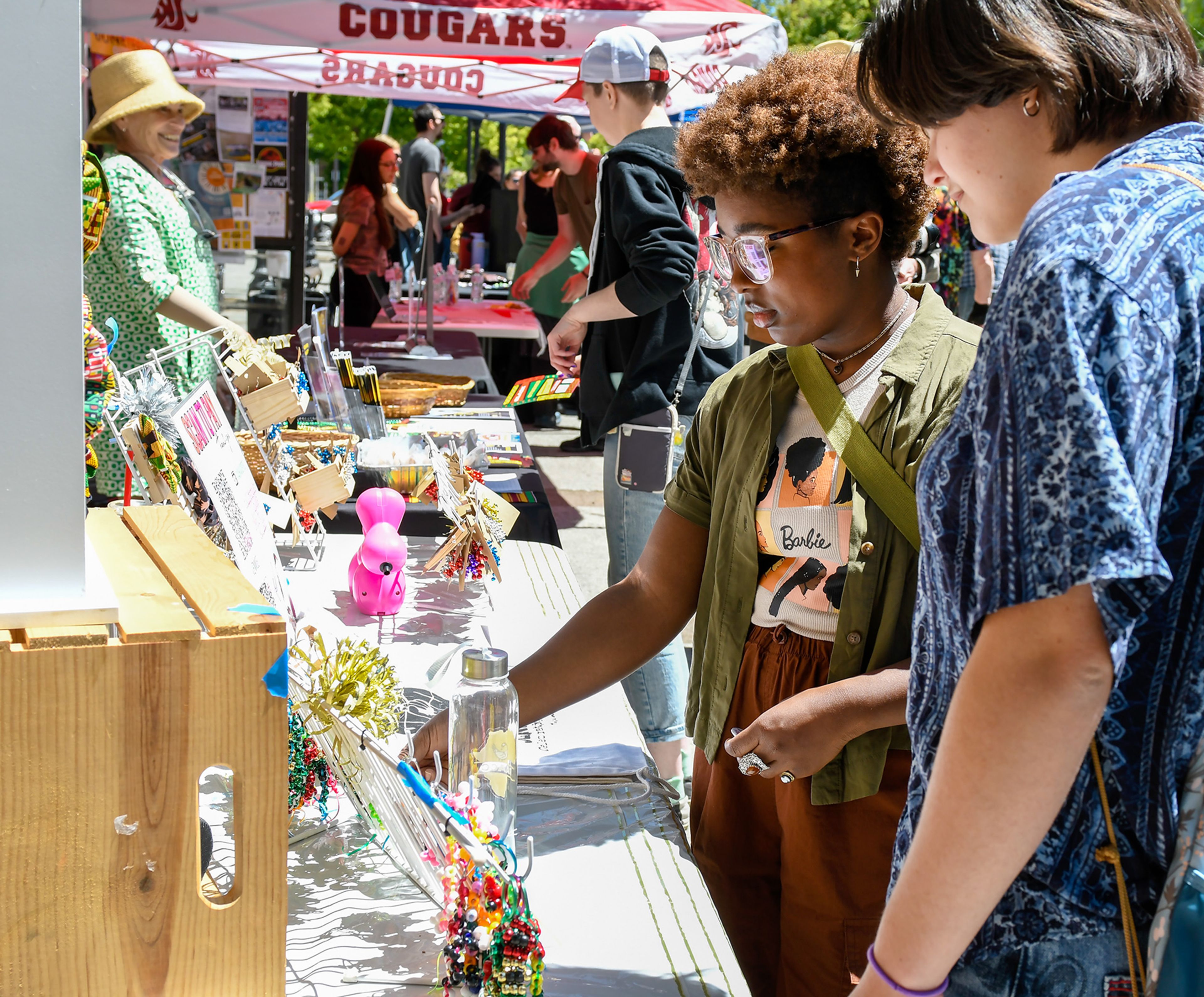 Emily Cook and Jessie Cook, right, look at crafts made by Bex Riehm, of the University of Idaho’s Black and African American Cultural Center, at the Juneteenth celebration in Friendship Square on Wednesday in Moscow.