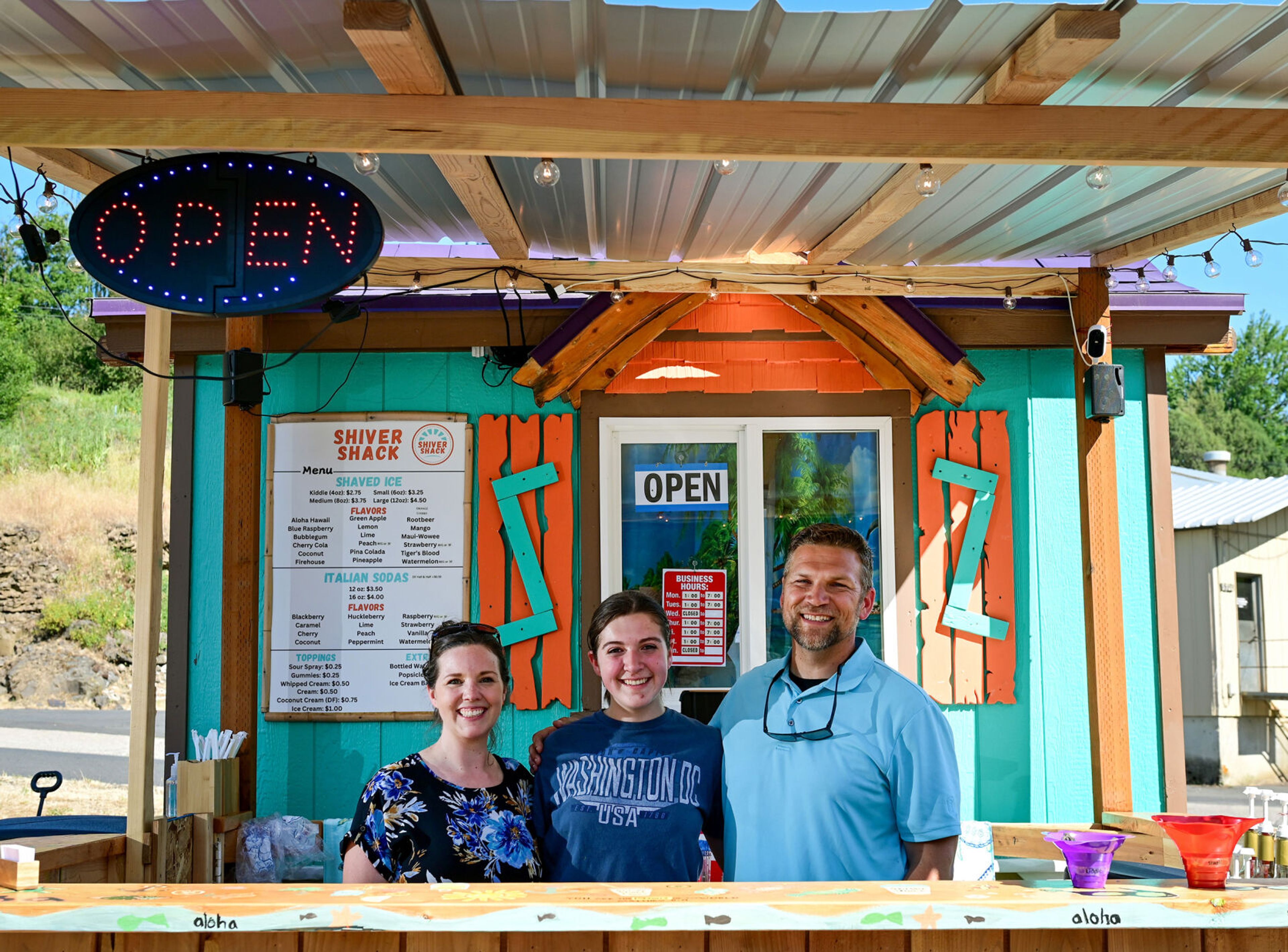 Parents Cassi and Dan Fitzgerald stand on either side of daughter Addyson Fitzgerald, 15, at new snow cone spot Shiver Shack in Pullman on Tuesday. Dan and Cassi are investors and consultants for their four children who operate the business, including Addyson, who serves as manager.