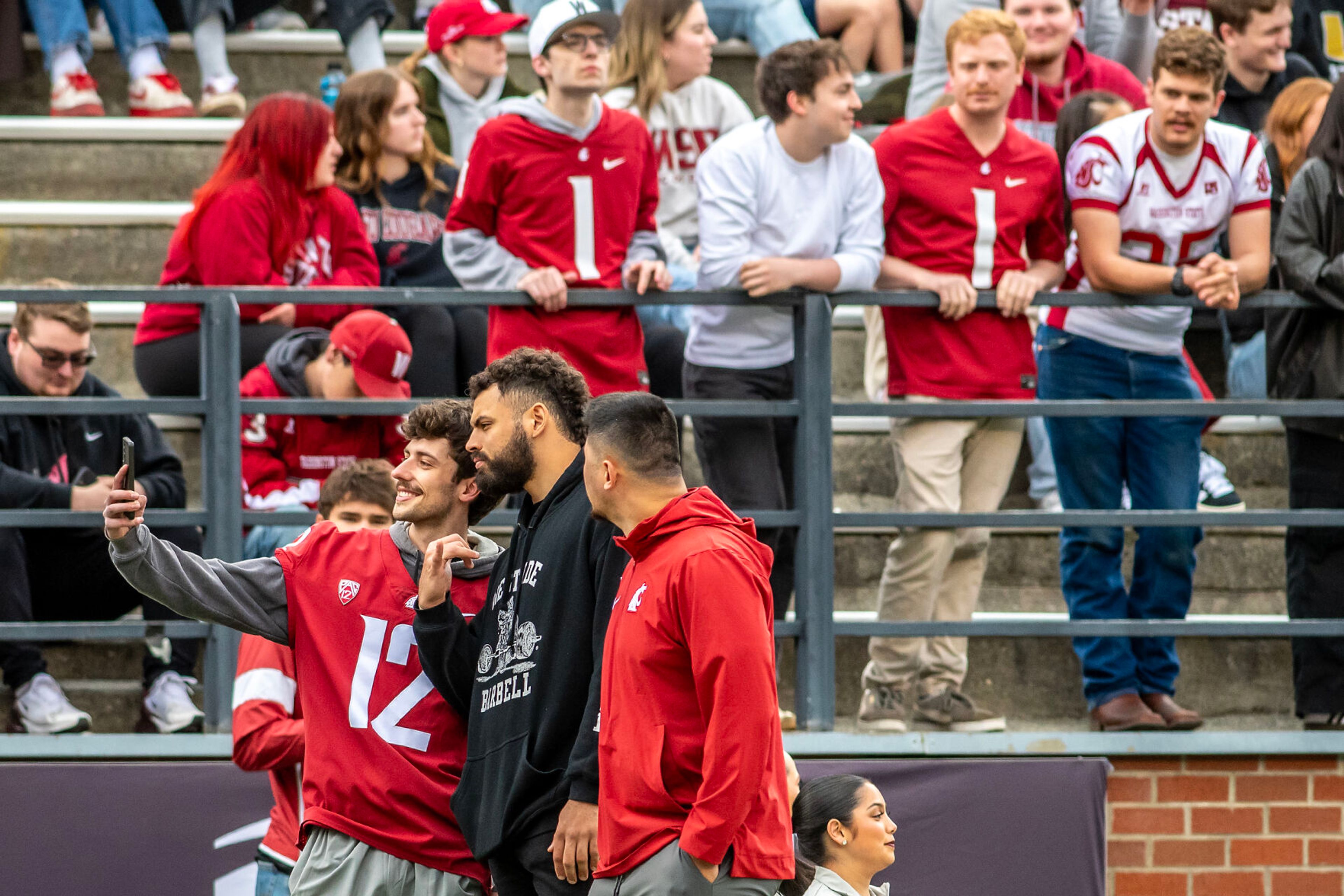 Former Cougar and current Seattle Seahawks player Abe Lucas takes a photo with a fan on the sidelines in a quarter of the Crimson and Gray Game at Washington State University in Pullman.