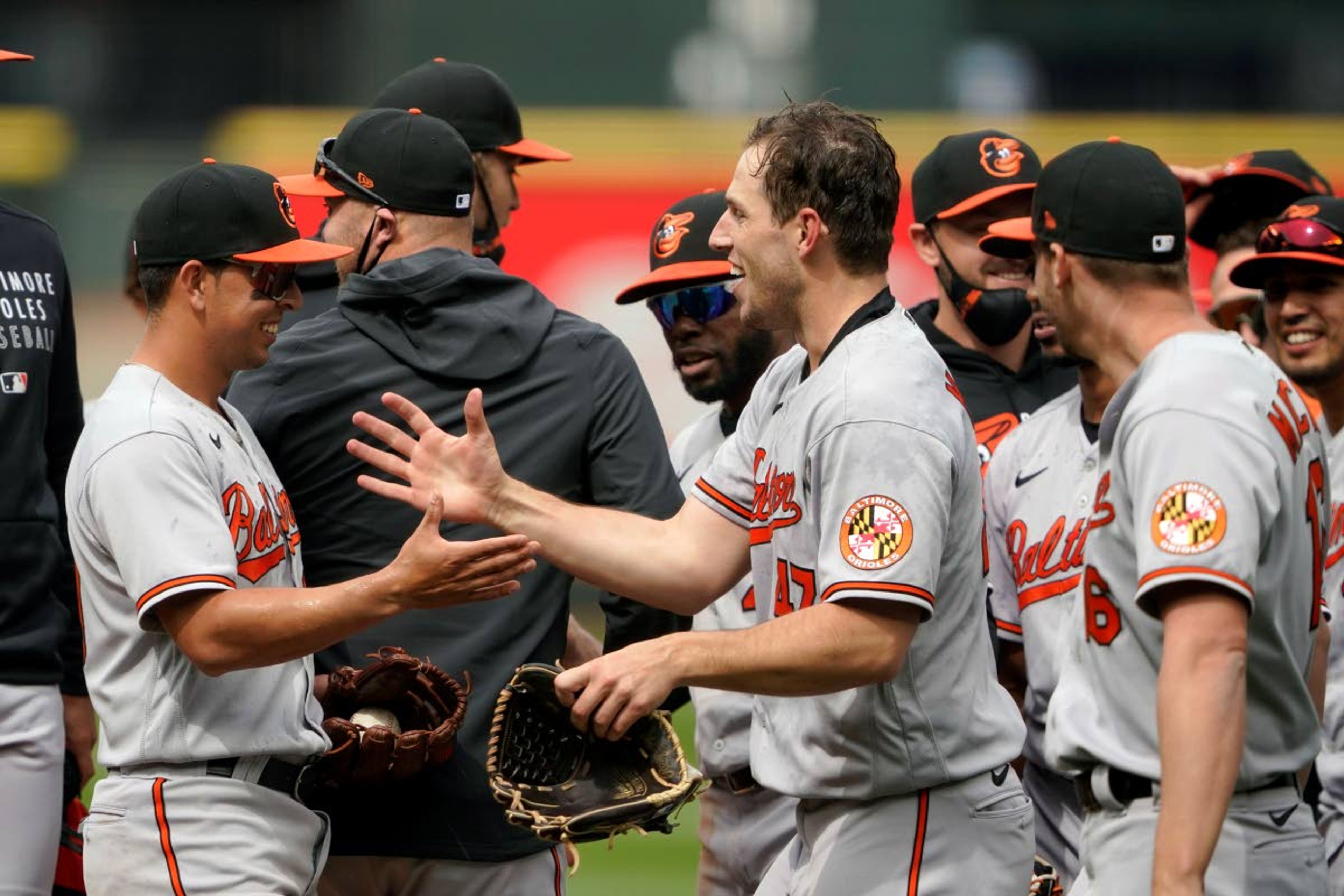 Baltimore Orioles starting pitcher John Means, center, greets shortstop Ramon Urias, left, after Means threw a no-hitter baseball game against the Seattle Mariners, Wednesday, May 5, 2021, in Seattle. Urias made the final out, snagging a line drive hit by by Seattle Mariners' J.P. Crawford. The Orioles won 6-0. (AP Photo/Ted S. Warren)