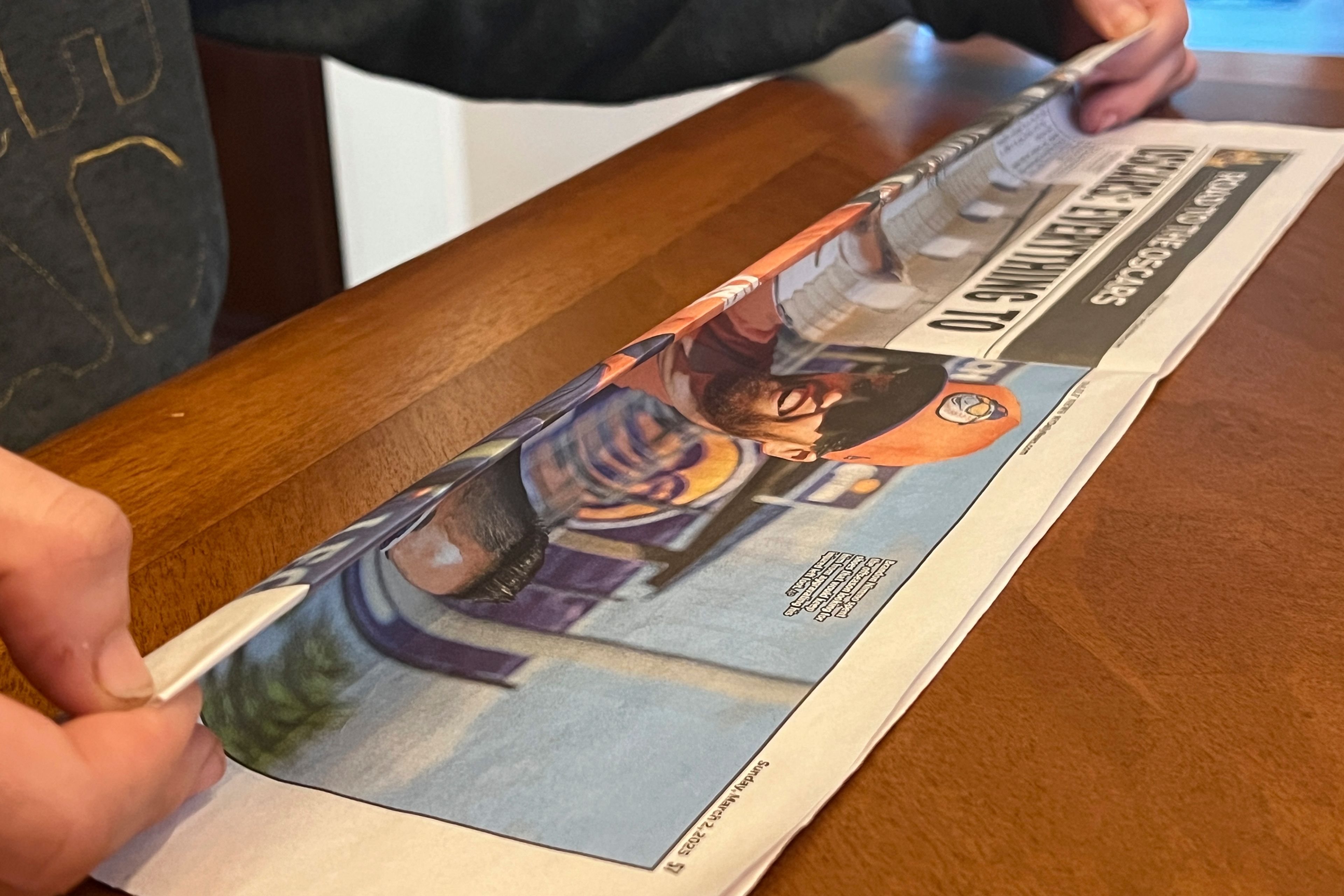 This March 2, 2025, image shows the first step in making a DIY seed pot from a sheet of newspaper. The 4-step process begins with folding a newspaper page in half lengthwise, then folding it a second time to achieve a long strip. (Jessica Damiano via AP)