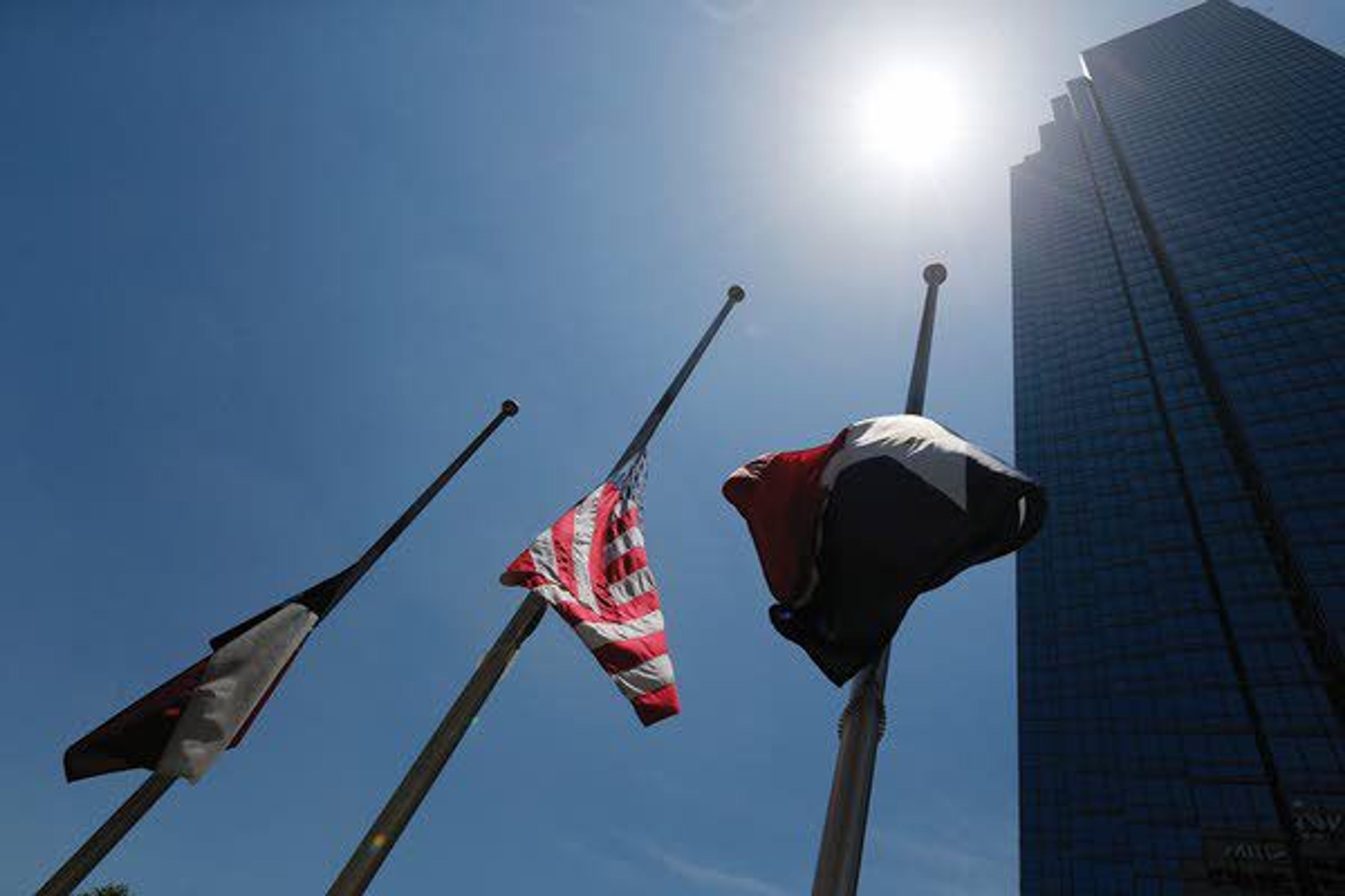 Flags fly at half staff Friday in a plaza at the area of the Thursday night attack on Dallas police officers. A peaceful protest in Dallas over the recent videotaped shootings of black men by police turned violent Thursday night as an unknown number of people shot at officers, killing five and injuring seven, as well as two civilians. (AP Photo/Gerald Herbert)