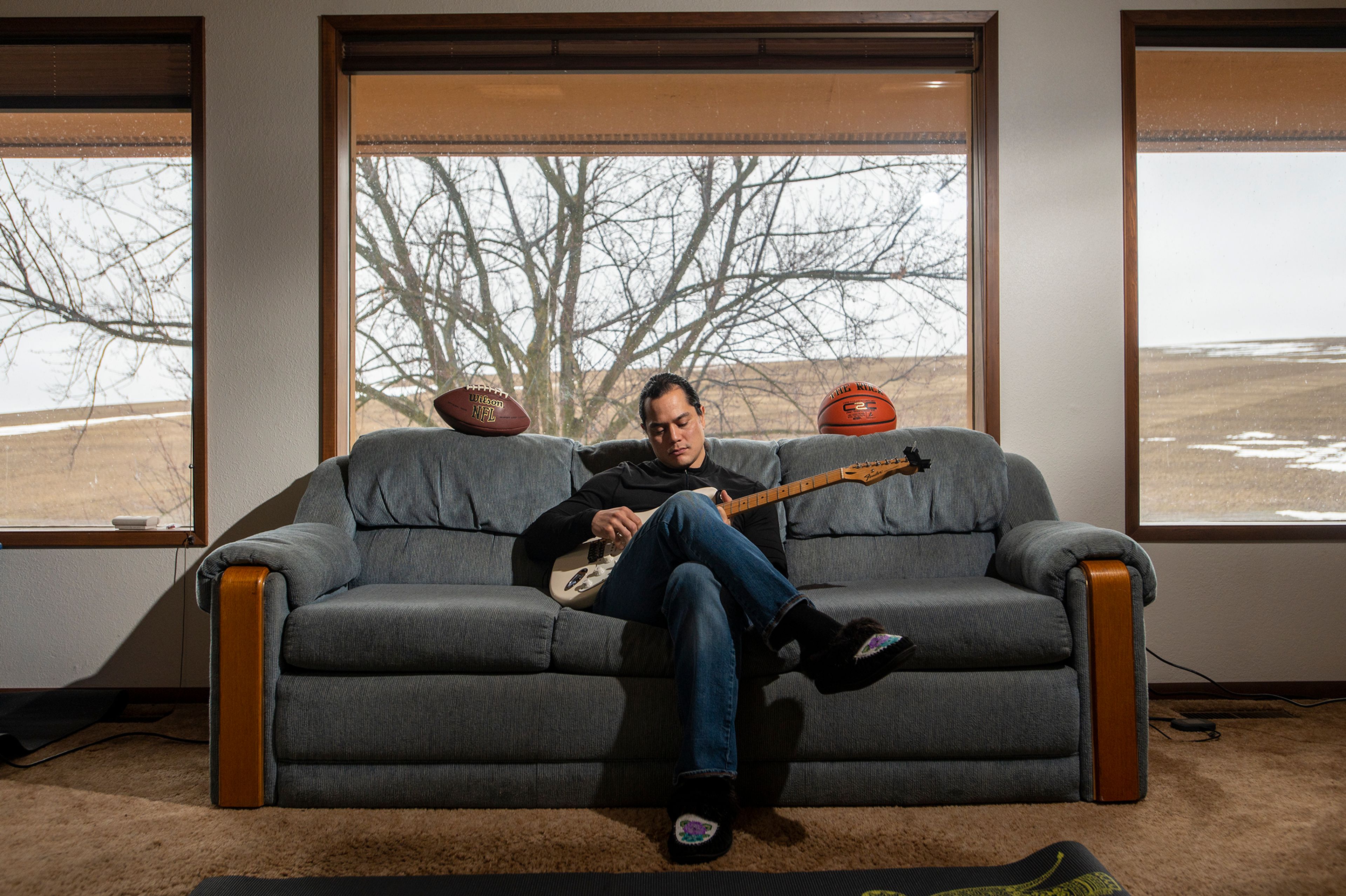 Ryan Harms, a former standout athlete at Pullman High School, strums his Fender guitar while posing for a portrait in Pullman late in 2021.