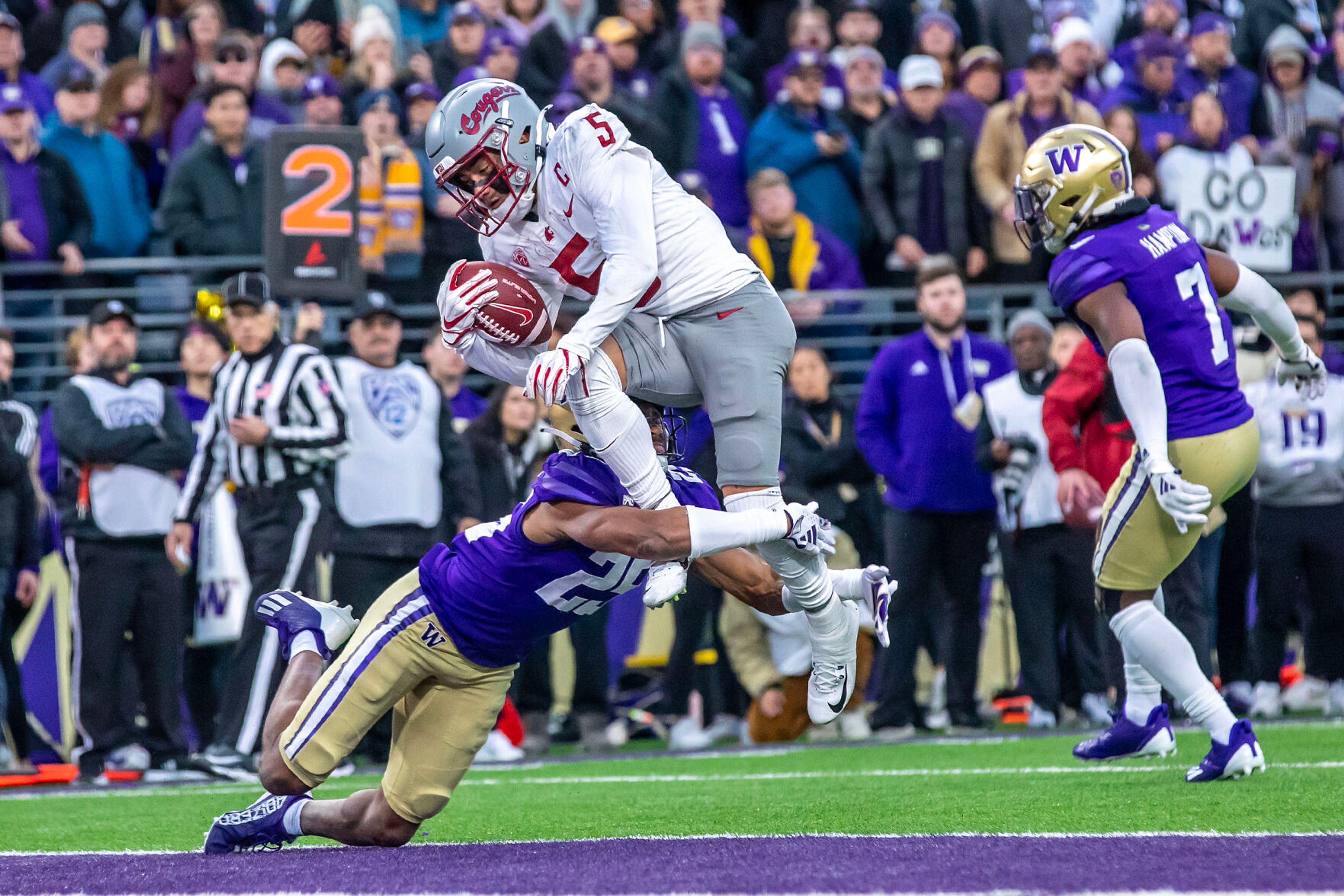 Washington State wide receiver Lincoln Victor (5) leaps over Washington cornerback Elijah Jackson (25) into the end zone to score a touchdown and tie the score during the Apple Cup on Saturday in Seattle.