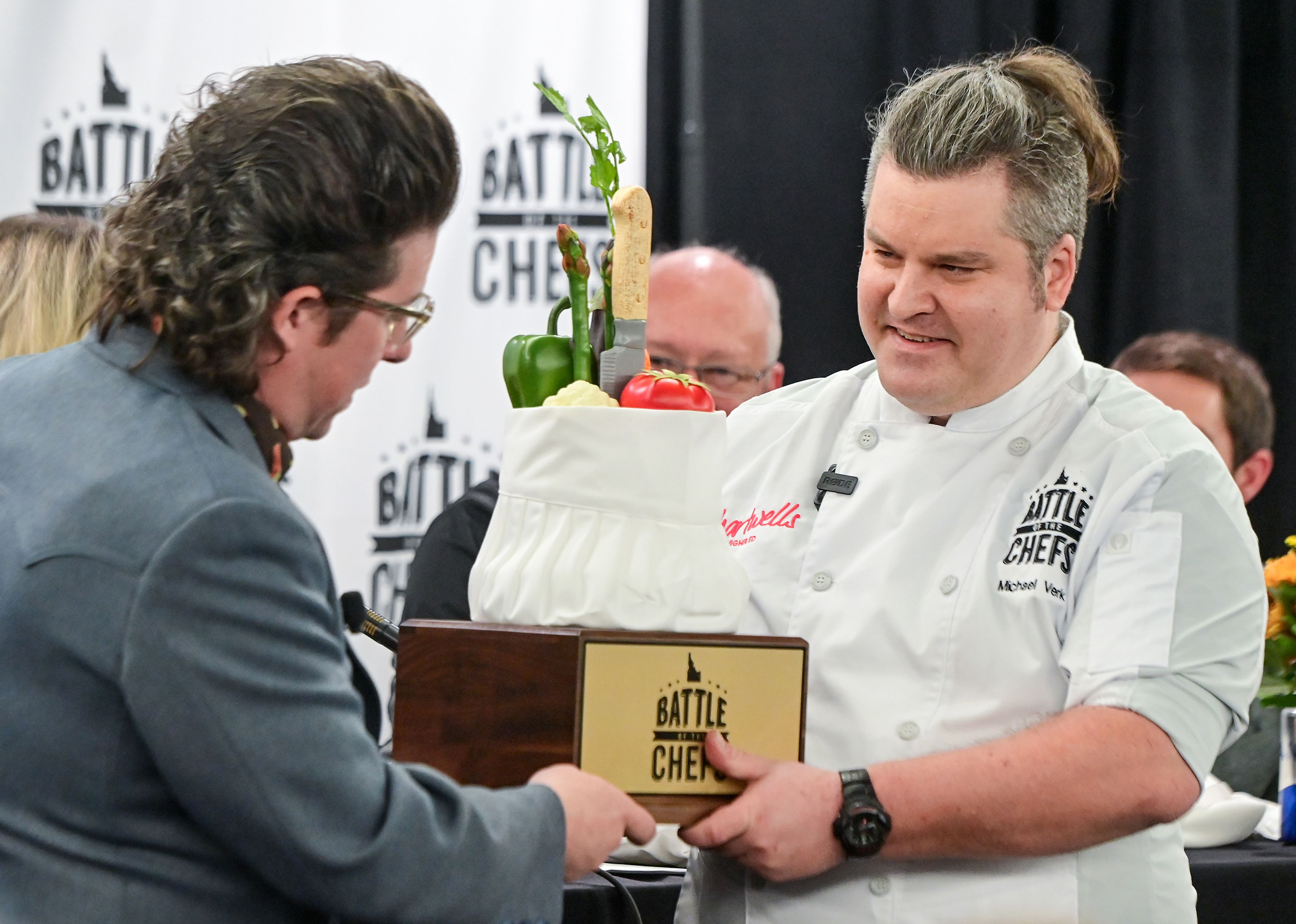 Celebrity chef Justin Warner awards the Battle of the Chefs trophy to Chef Michael Verk, right, an executive chef with the University of Idaho’s Idaho Eats, Wednesday after a live judge tasting and voting at The Eatery on campus in Moscow. The chefs were challenged with making a dish using local ingredients within a short period of time.