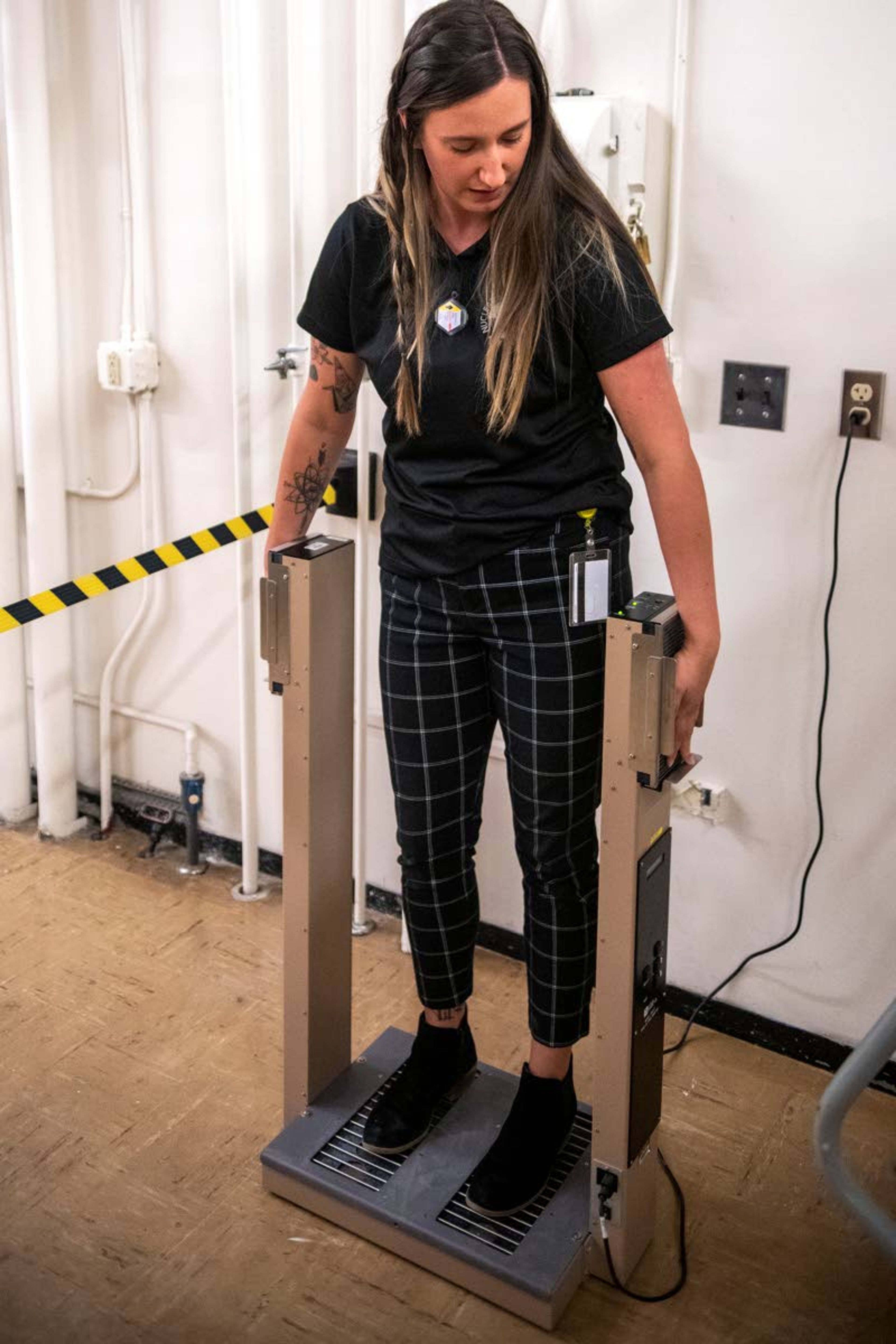 Before exiting the room containing the nuclear reactor core, research operations engineer Maddison Heine stands on a hand-foot contamination monitor to detect any emitted radionuclides on her hands, feet or clothing.