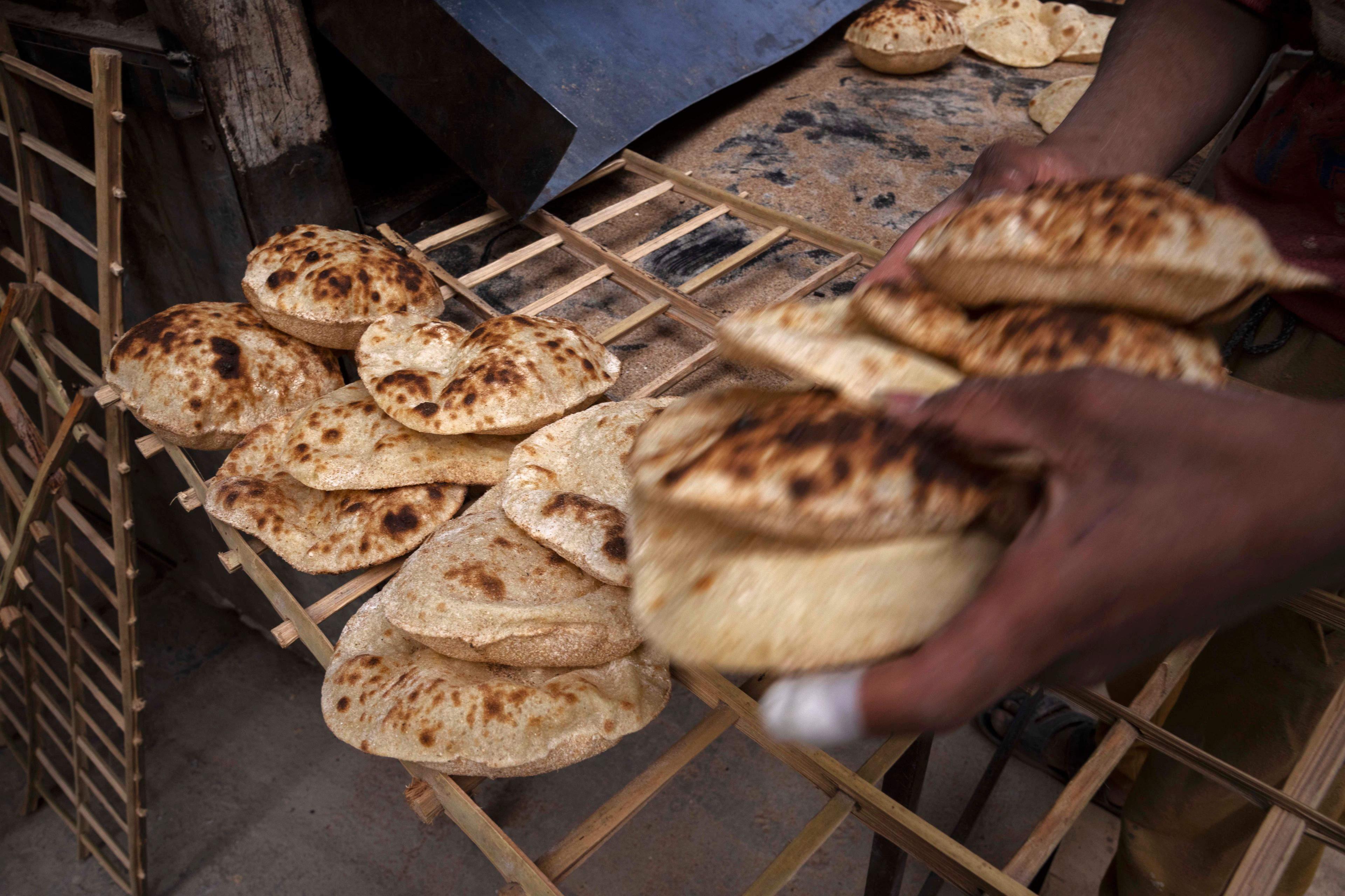 FILE - A worker collects Egyptian traditional 'baladi' flatbread, at a bakery, in el-Sharabia, Shubra district, Cairo, Egypt, Wednesday, March 2, 2022. The war has raised the specter of food shortages and political instability in countries that rely on affordable grain imports like Egypt. (AP Photo/Nariman El-Mofty, File)