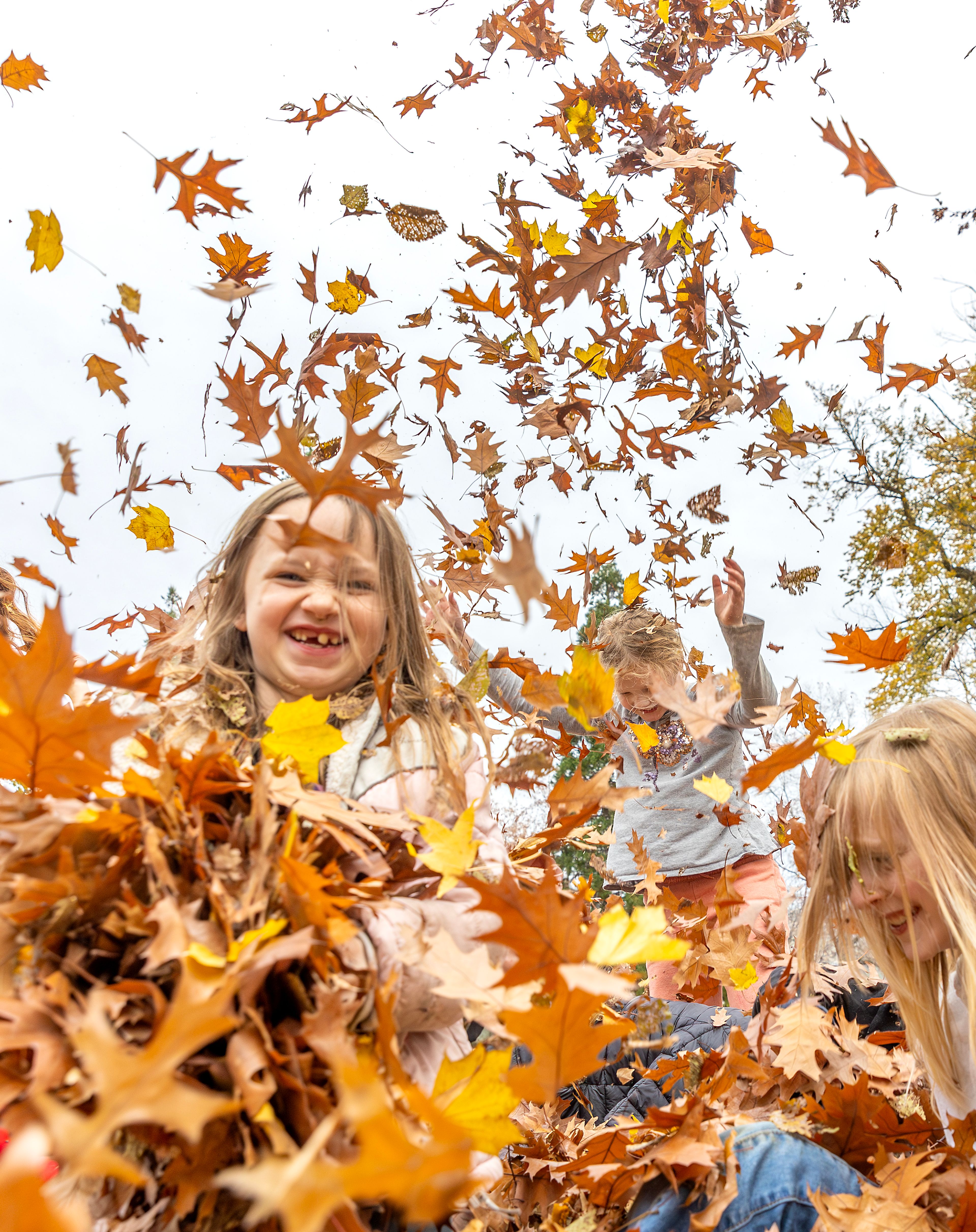 Maya Pearson, middle, throws some leaves in the air outside Children's House Montessori School at Pioneer Park Wednesday in Lewiston.