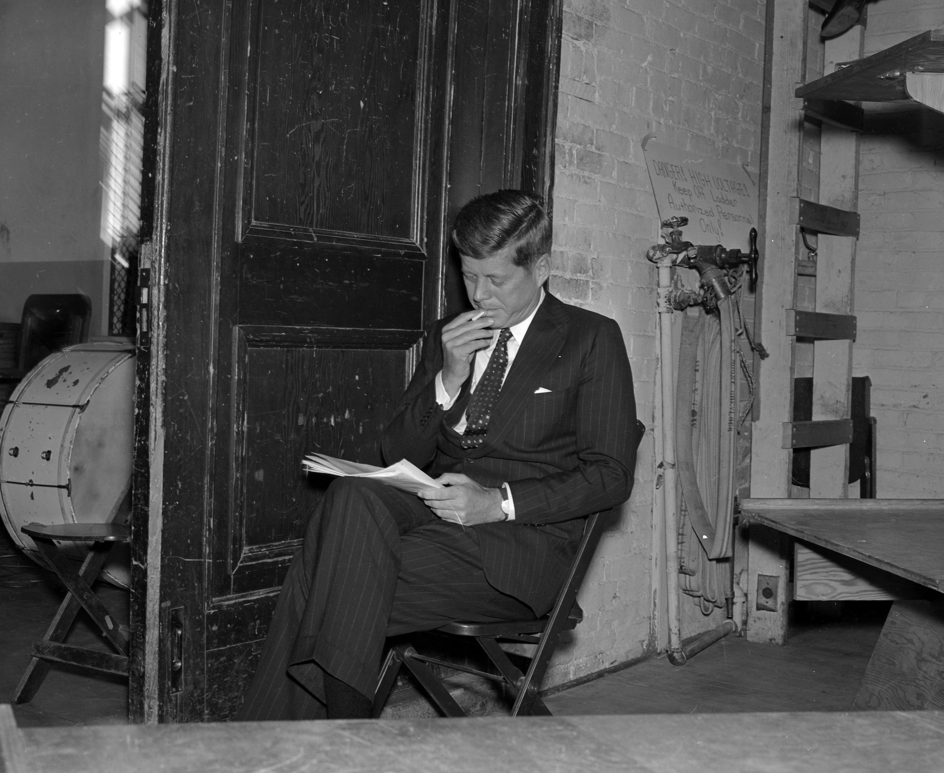 Presidential candidate John F. Kennedy grabs a smoke backstage in Bryan Hall as he reviews his speech on the Washington State University campus in Pullman.