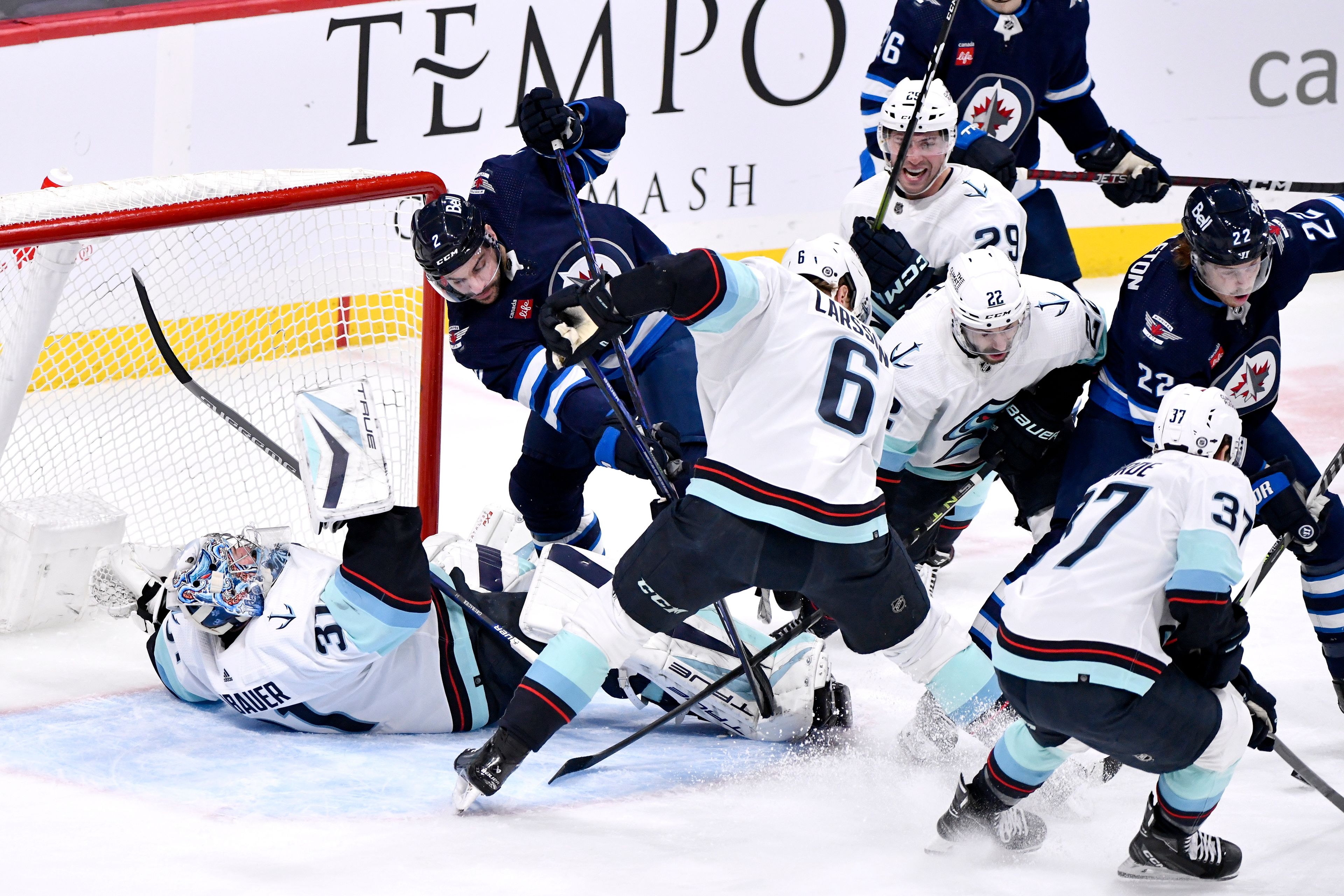 Seattle Kraken goaltender Philipp Grubauer (31) is knocked over by Winnipeg Jets' Dylan Demelo (2) during the first period of an NHL game in Winnipeg, Manitoba on Tuesday Feb. 14, 2023. (Fred Greenslade/The Canadian Press via AP)