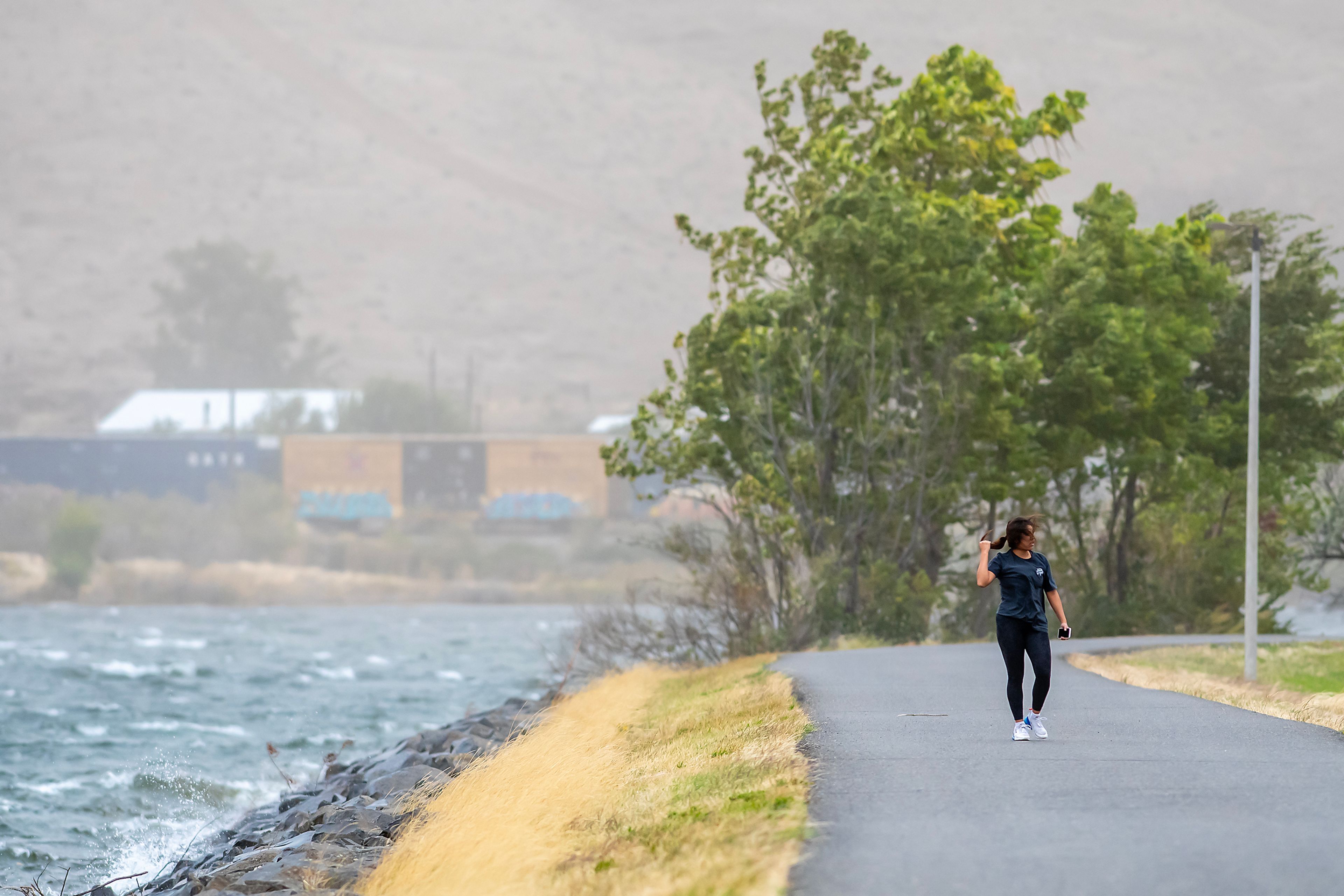 A person walks down the Lewiston Levee Parkway trail as heavy winds gust across the region Friday in Lewiston.,