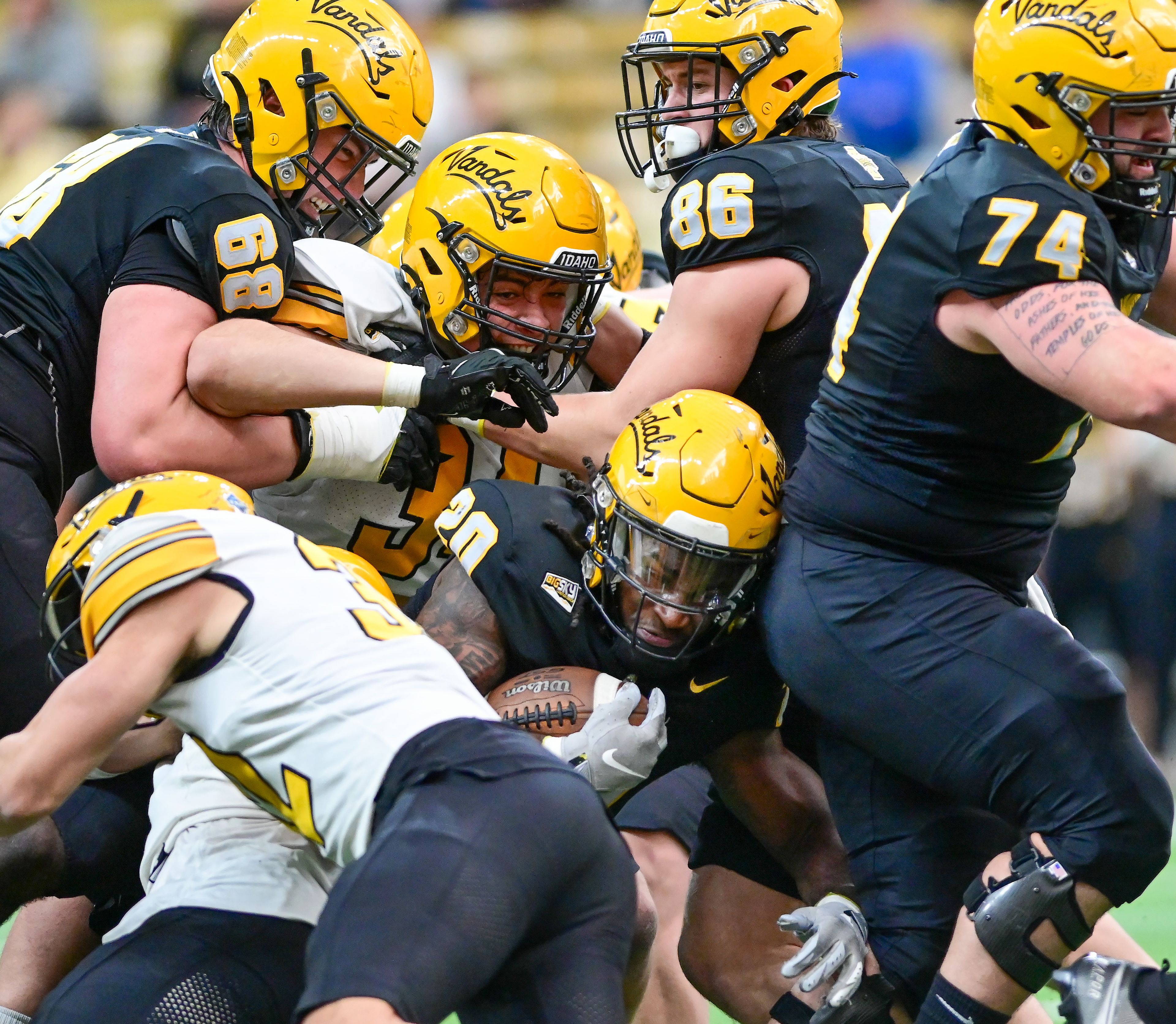 Vandals running back Elisha Cummings (20) is tackled as teammates work to fight off opposing defenders at the annual spring game at the P1FCU Kibbie Dome in Moscow on Friday.