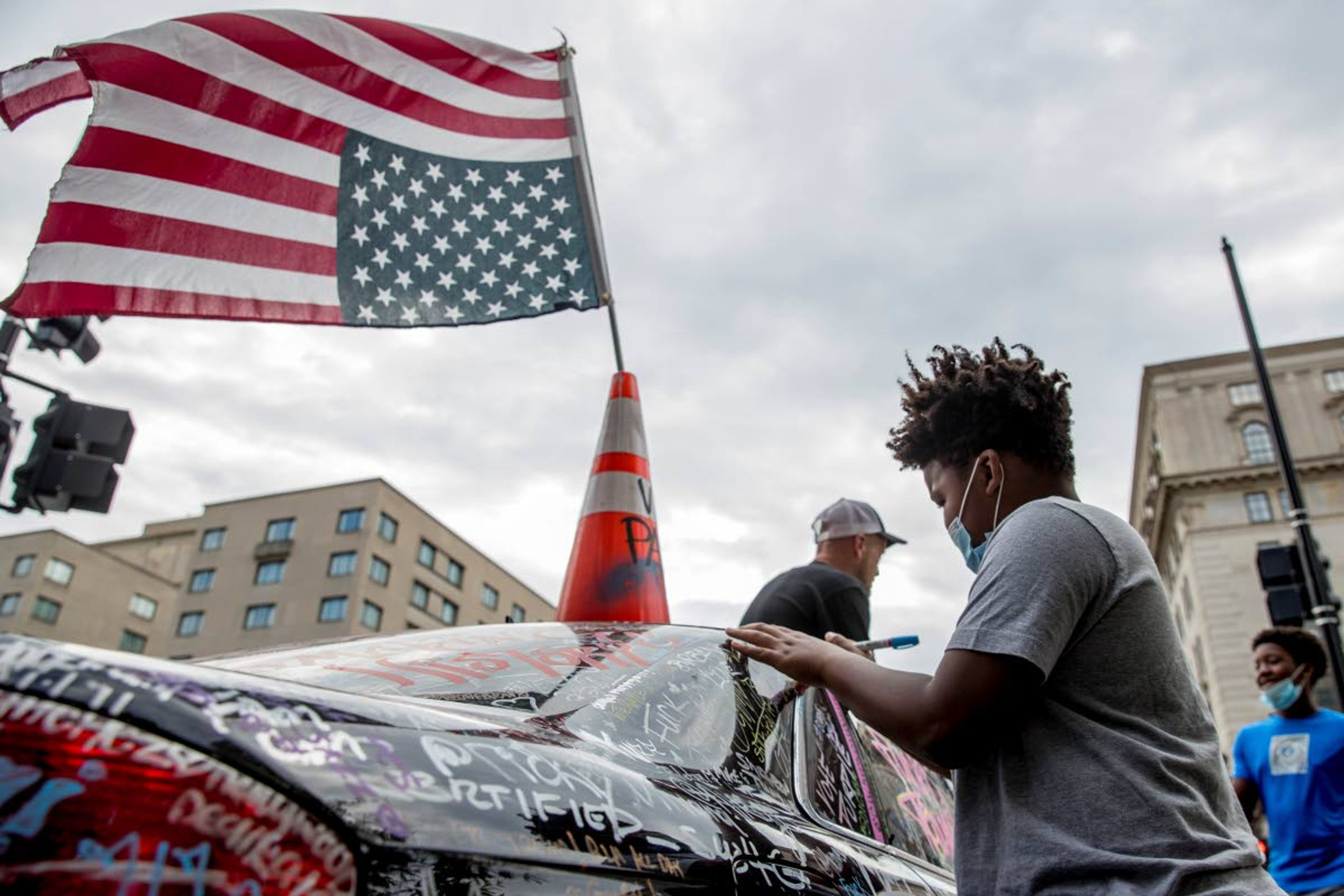 Rylan Hunt, 10, of Woodbridge, Va., signs a car on 16th Street Northwest renamed Black Lives Matter Plaza near the White House, Friday, June 19, 2020, in Washington. (AP Photo/Andrew Harnik)