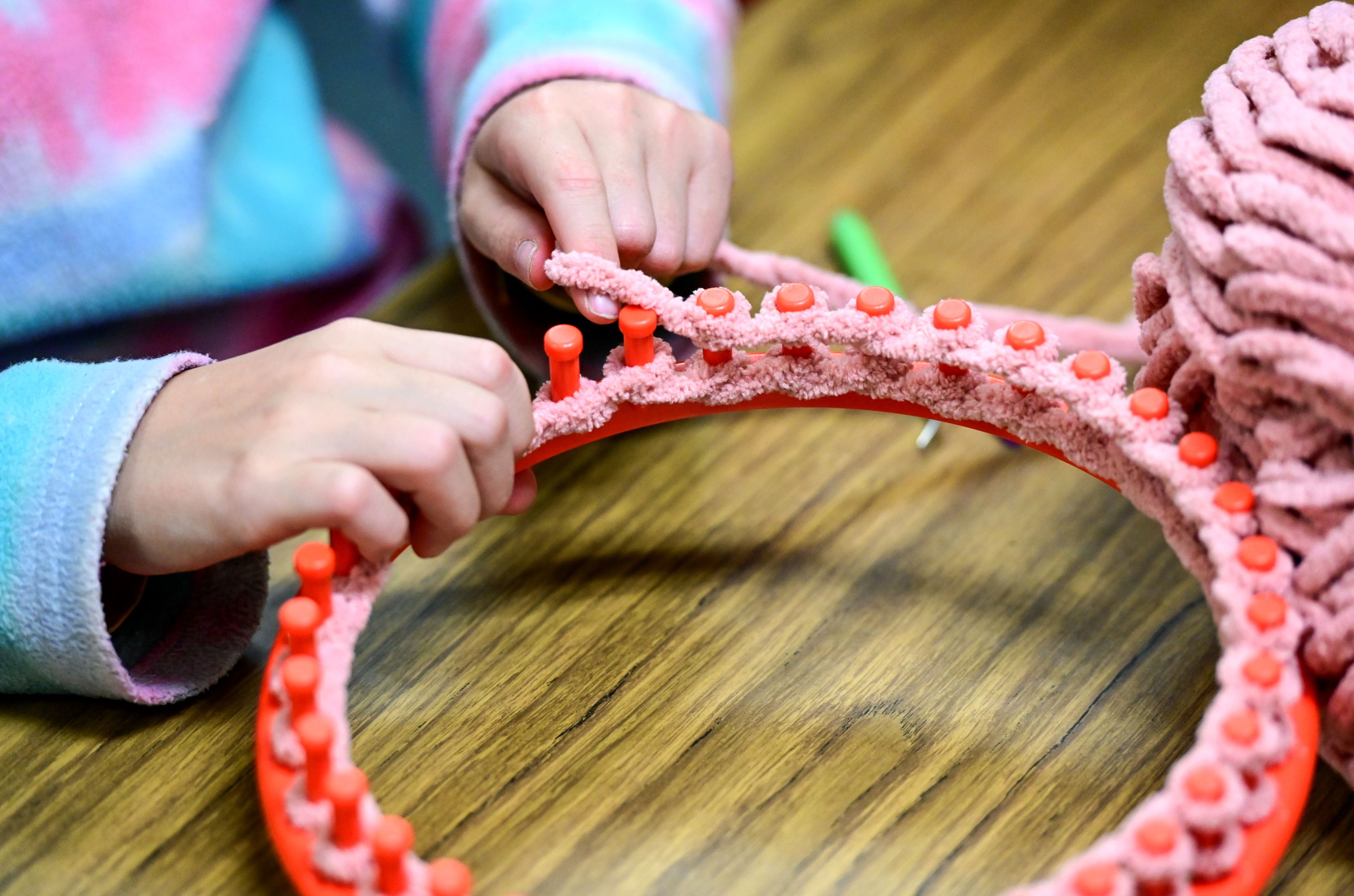 Fourth-grader Ari Richardson wraps pink yarn around a round loom after school at Lena Whitmore Elementary School in Moscow on Monday.