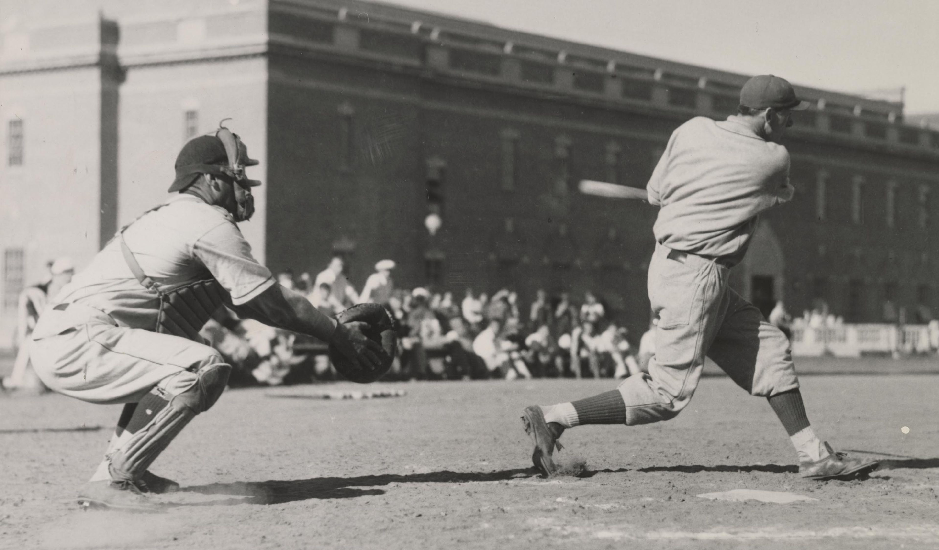 The first Cougar major leaguer, Art McLarney, makes contact for a single against Oregon in the early 1930s. The southwest corner of Bohler Gym is in the background.