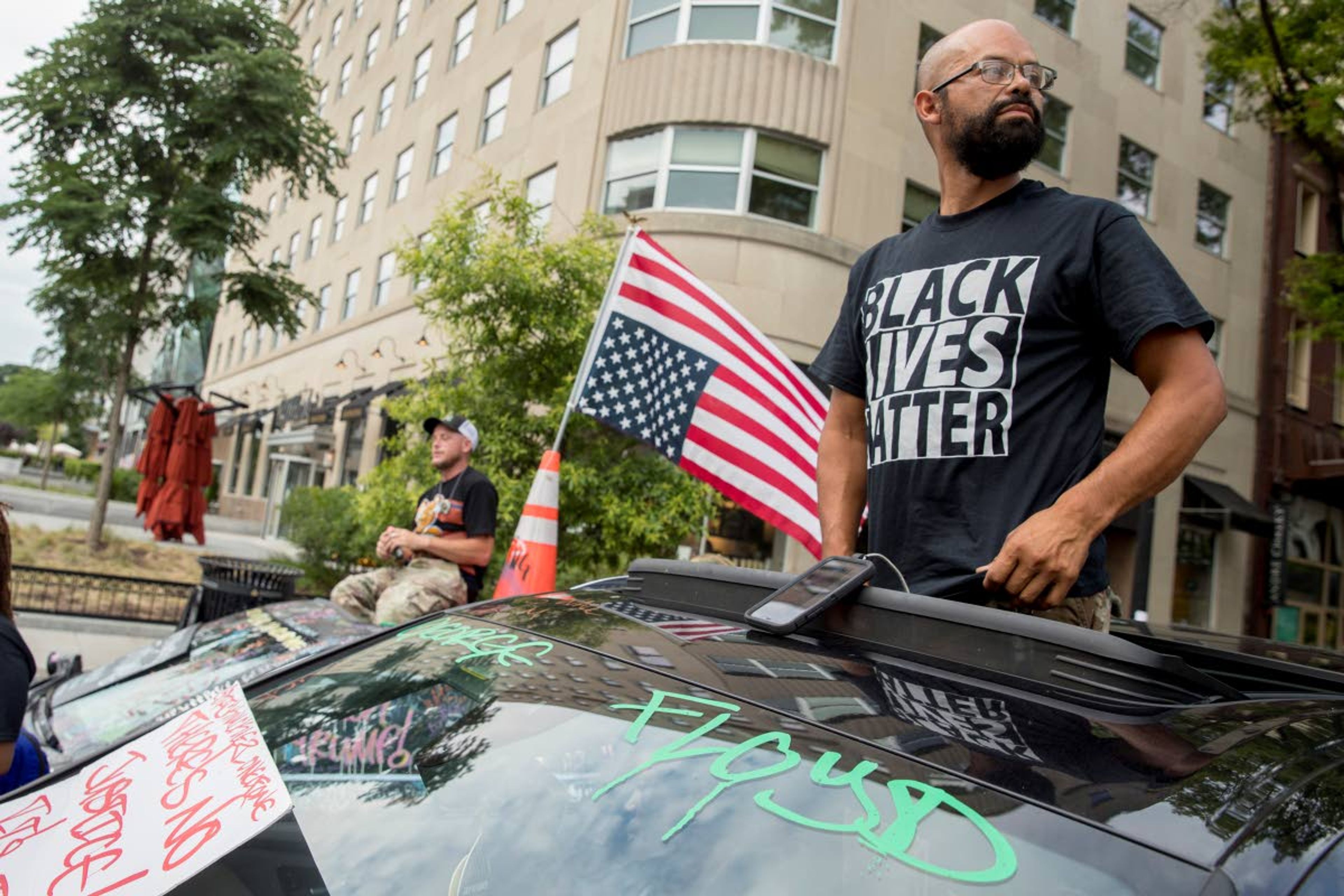 George Floyd's name is written on the windshield as John Coy wears a shirt that reads Black Lives Matter and stands through his sunroof at 16th Street Northwest renamed Black Lives Matter Plaza near the White House, Friday, June 19, 2020, in Washington. (AP Photo/Andrew Harnik)