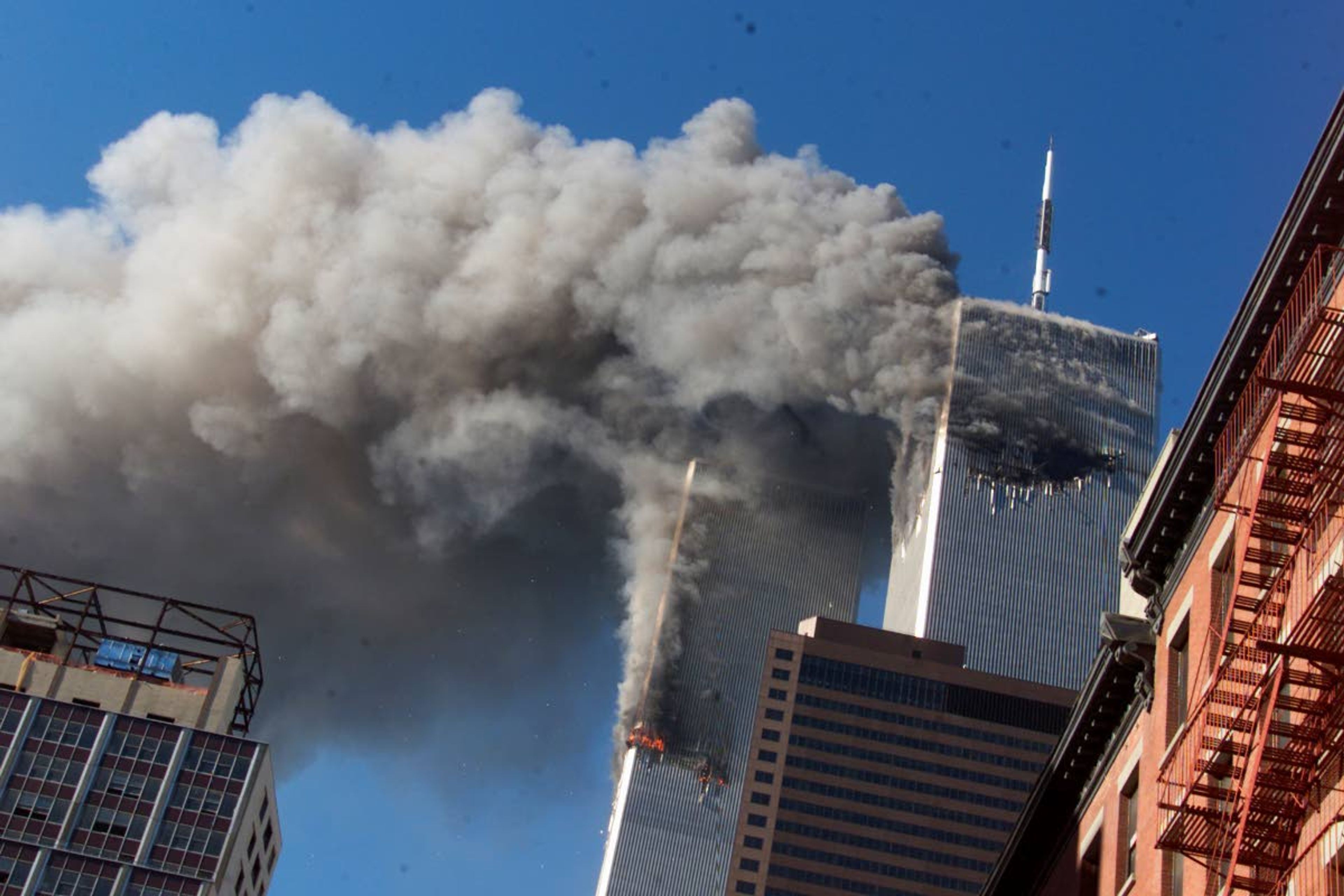 FILE - In this Sept. 11, 2001, file photo, smoke rises from the burning twin towers of the World Trade Center after hijacked planes crashed into the towers, in New York City. The coronavirus pandemic has reshaped how the U.S. is observing the anniversary of 9/11. The terror attacks' 19th anniversary will be marked Friday, Sept. 11, 2020, by dueling ceremonies at the Sept. 11 memorial plaza and a corner nearby in New York. (AP Photo/Richard Drew, File)