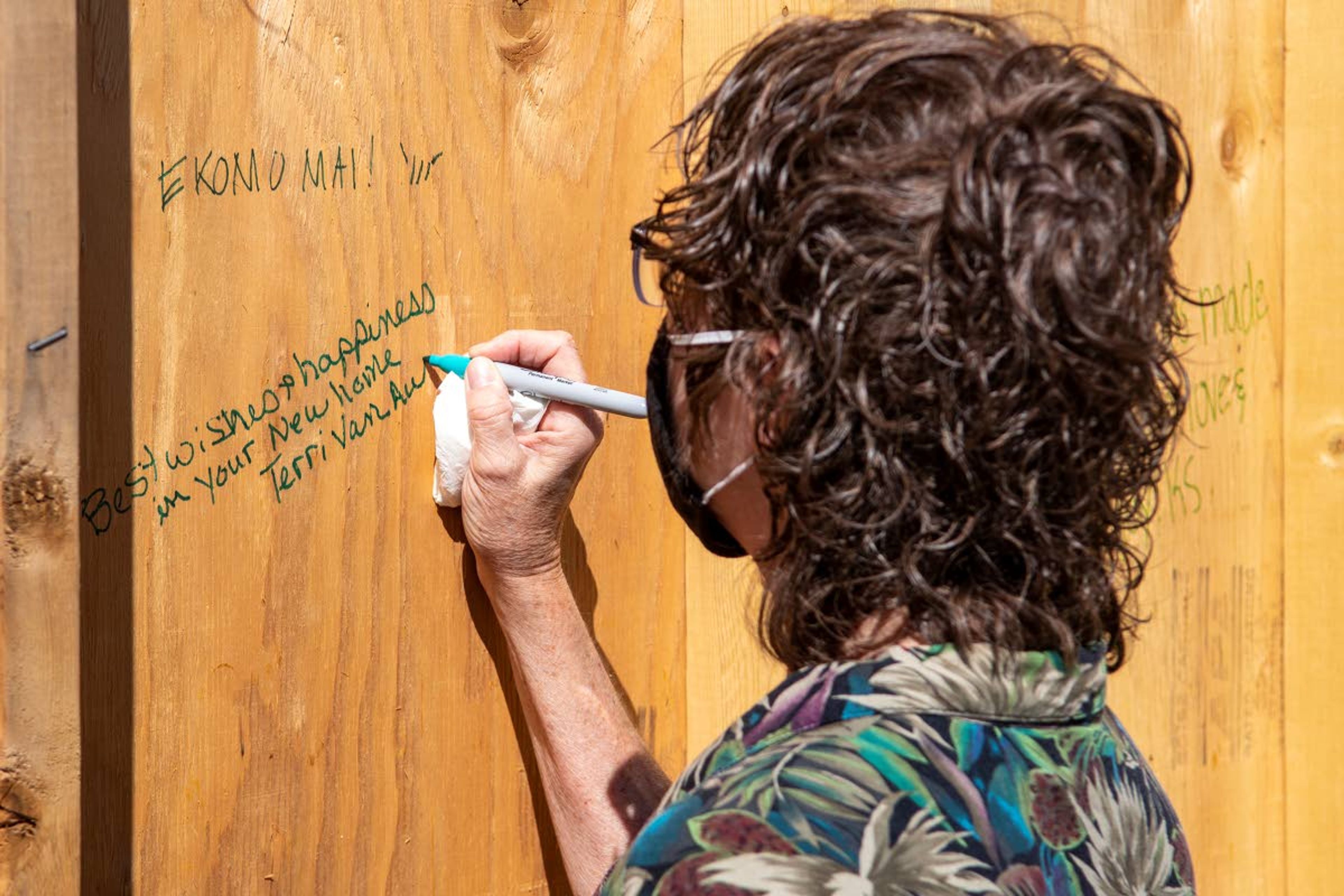 Guest Terri Van Auken, of Colfax, leaves a positive message on a wall during a celebration of raising the final wall of an energy efficient home in Uniontown on Thursday afternoon.